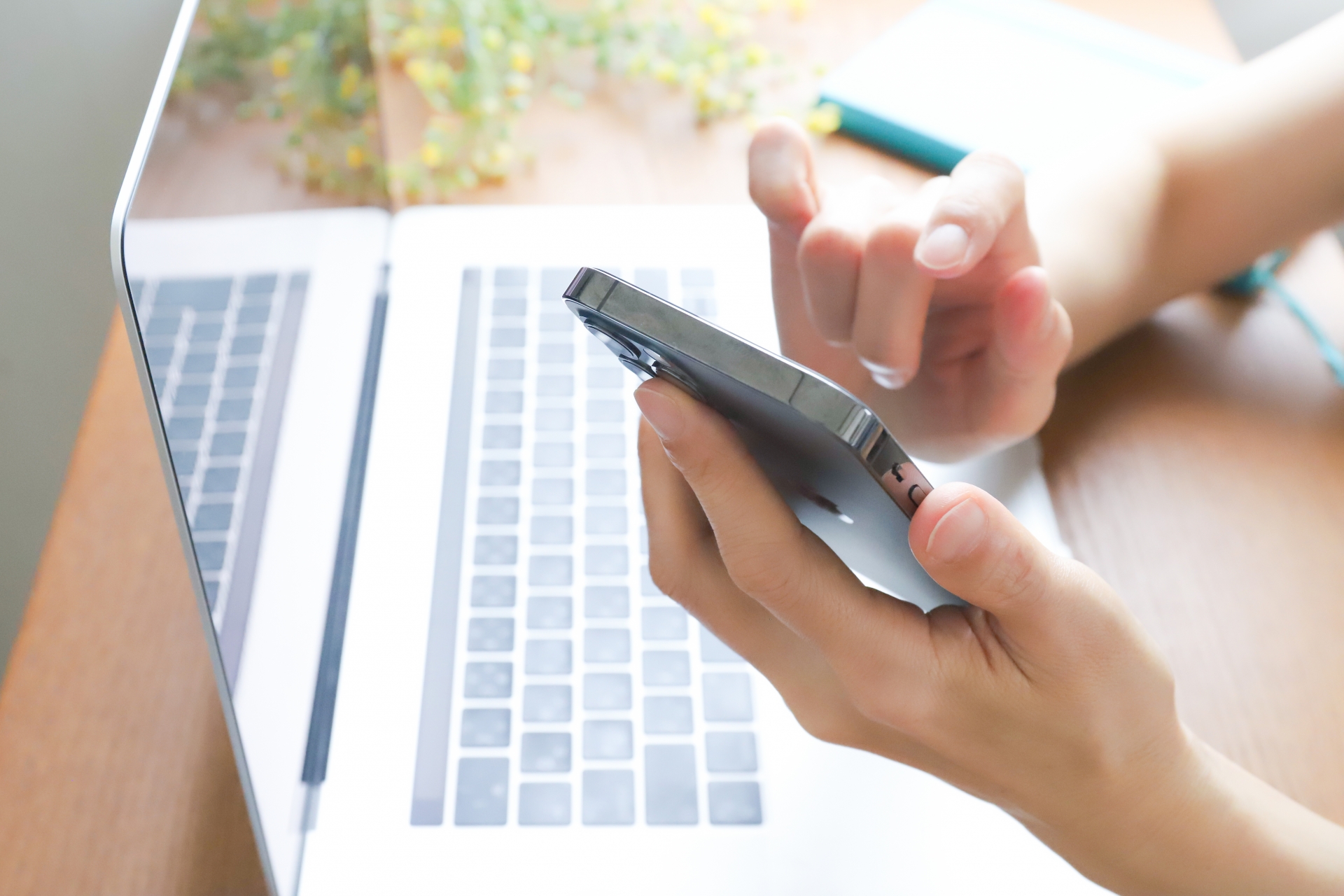 PCの上でスマホを操作する人の手元