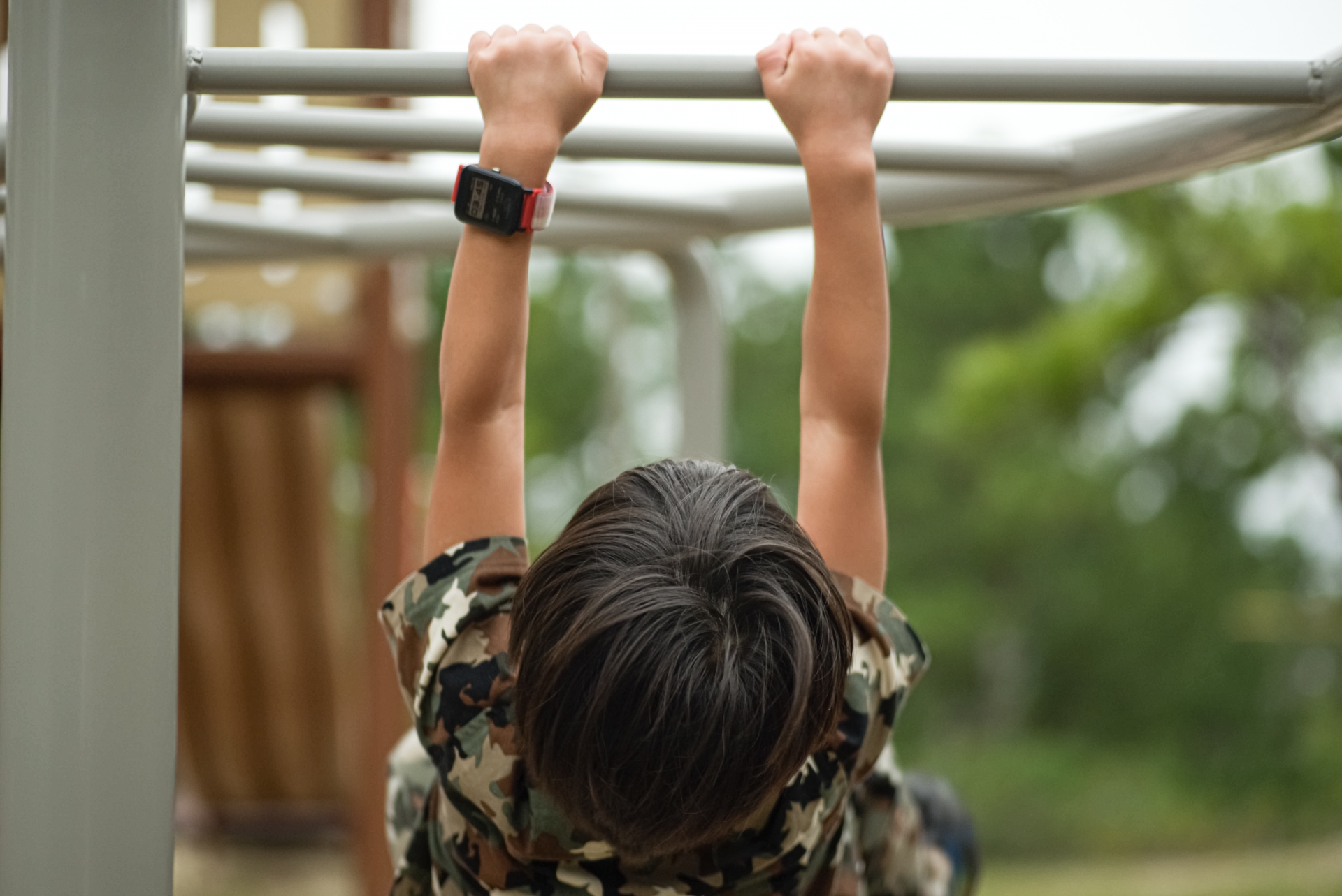 公園で雲梯にぶら下がる男の子