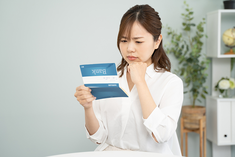 通帳を見て考え込む女性