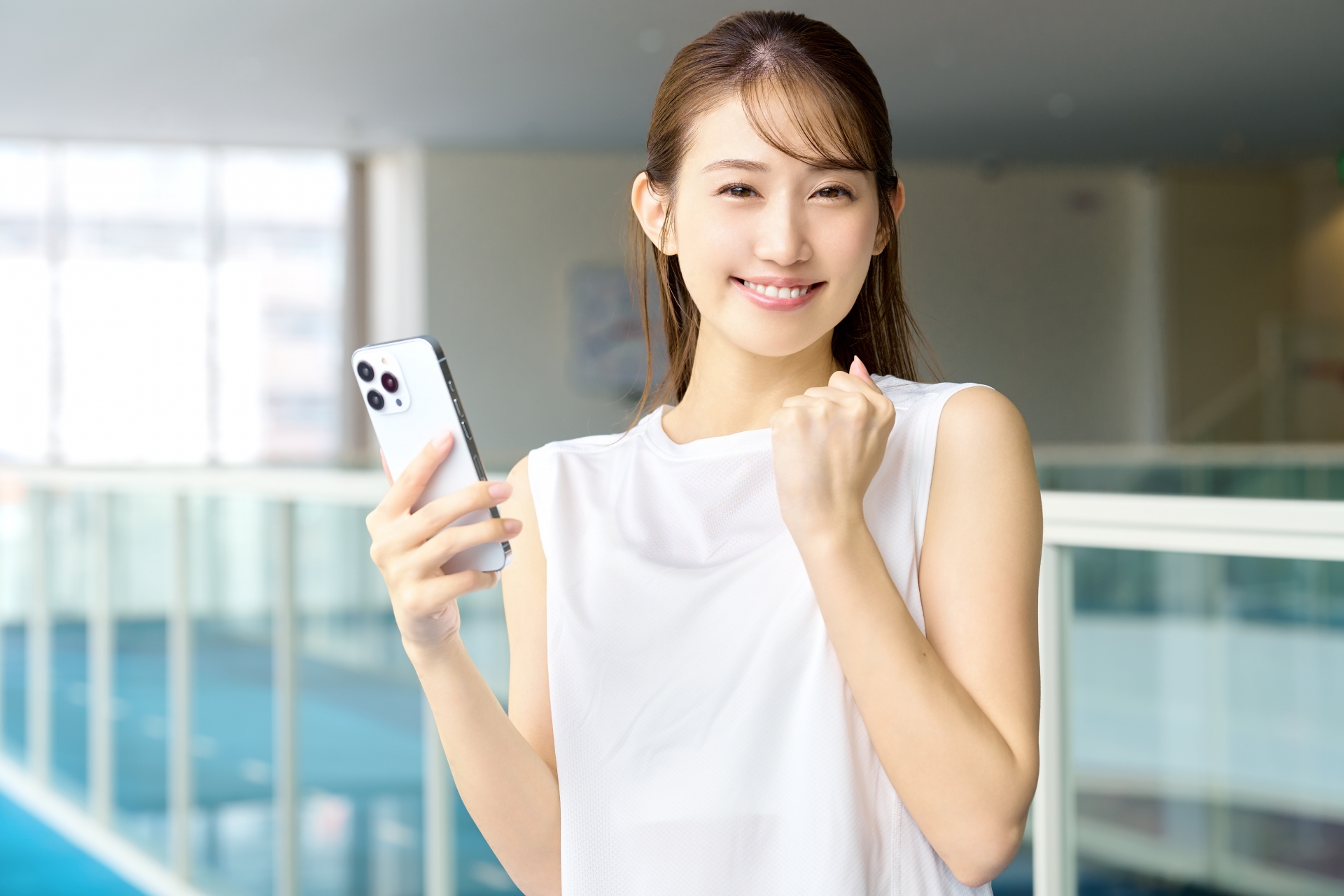 スマホを持ってガッツポーズをする笑顔の女性