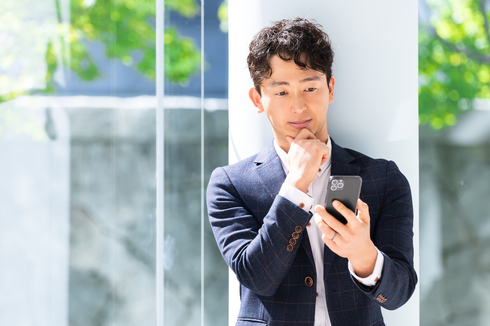 スマホの画面を見て考える男性ビジネスマン