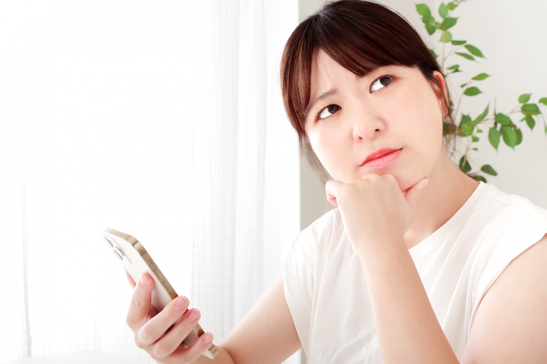 頬杖をついて考え事をする若い女性