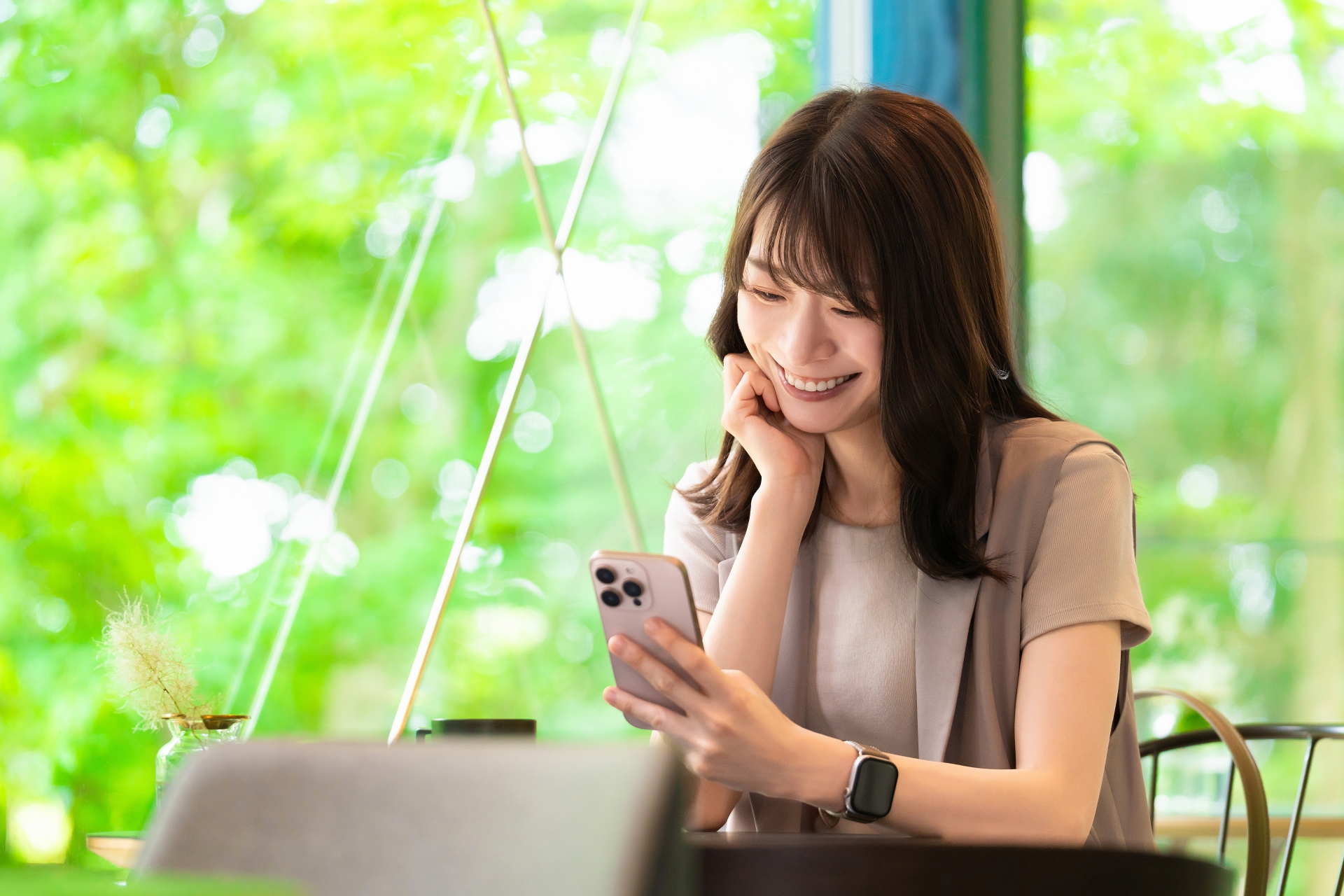 カフェでスマホを使う笑顔の女性