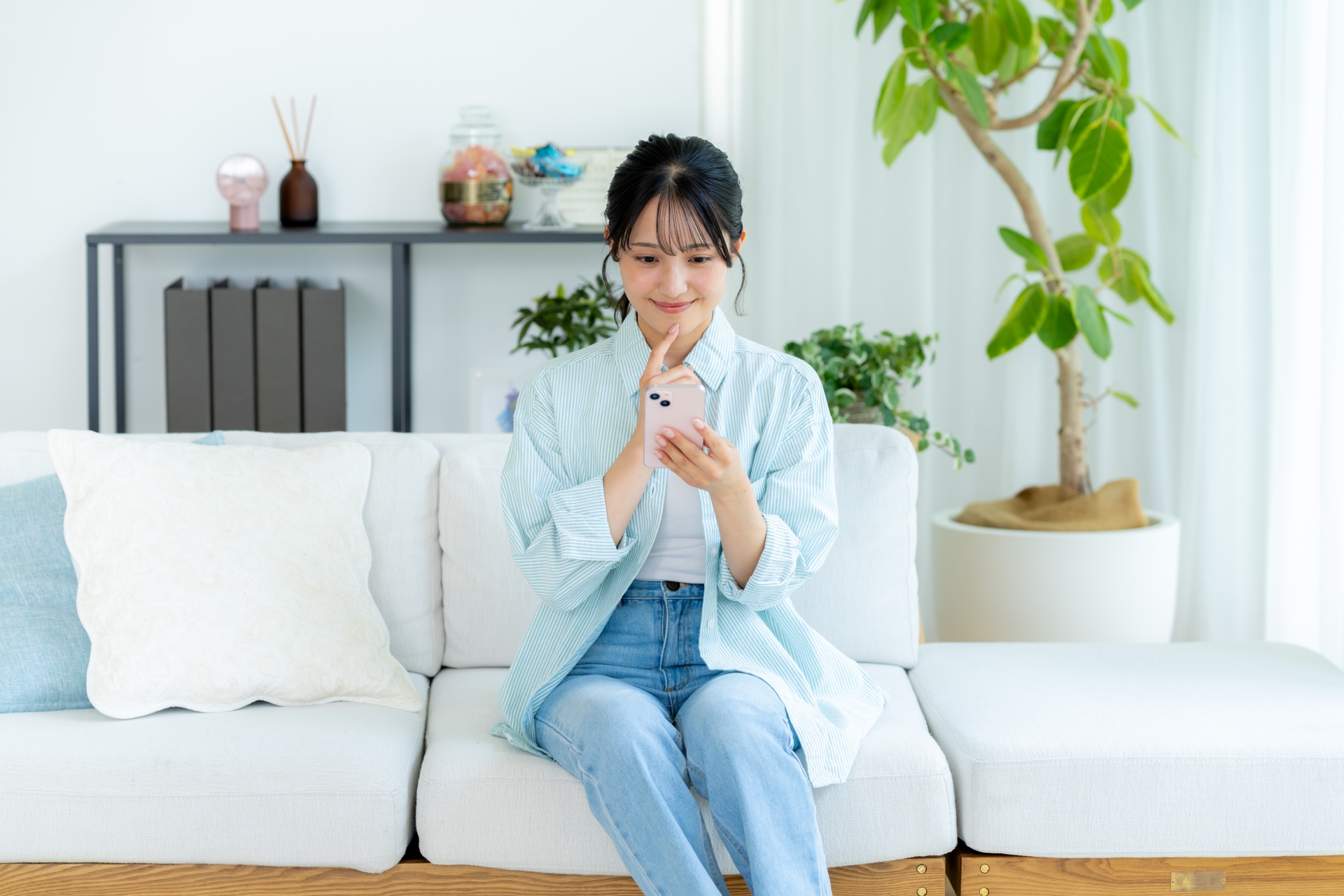 部屋でスマホを操作する若い女性