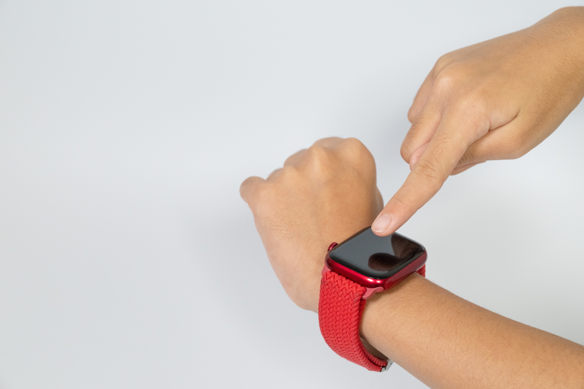 スマートウォッチを操作する赤いバンドの手