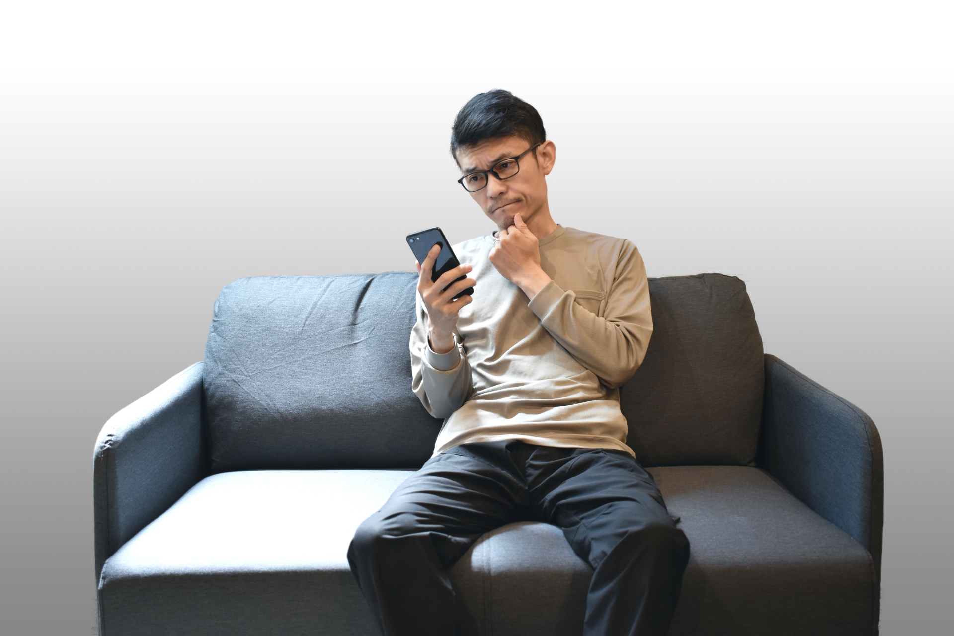 ソファーでスマホを見る男性