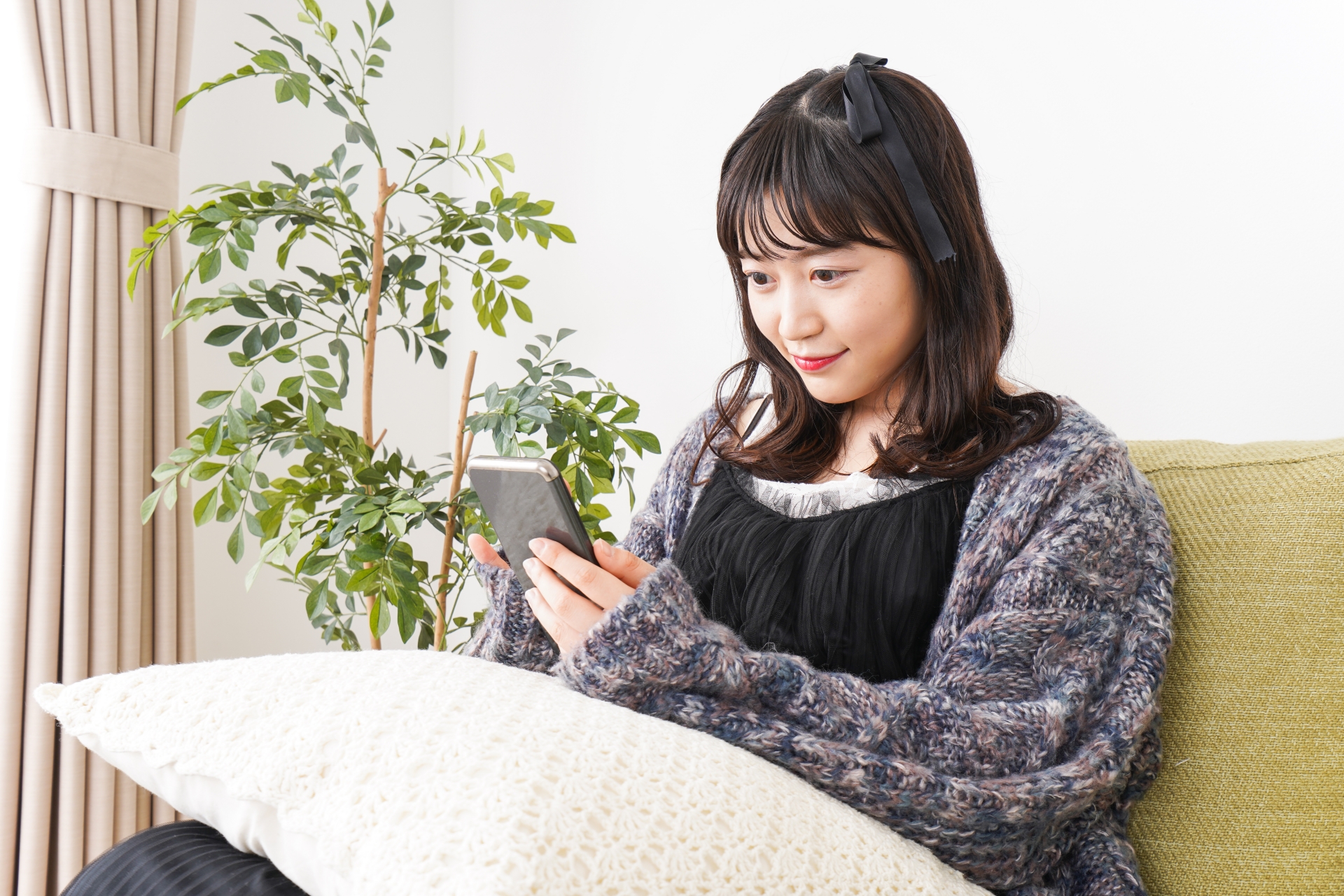 家でスマートフォンを使う若い女性