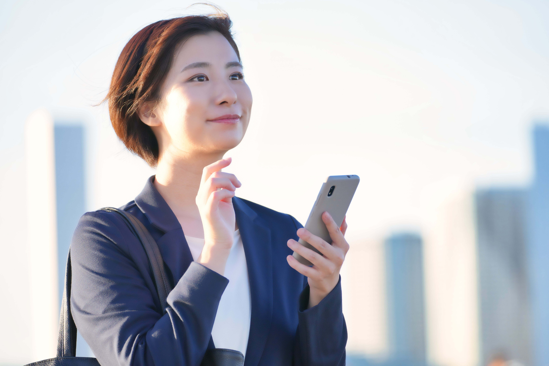 スマホを持ち遠くを見る女性