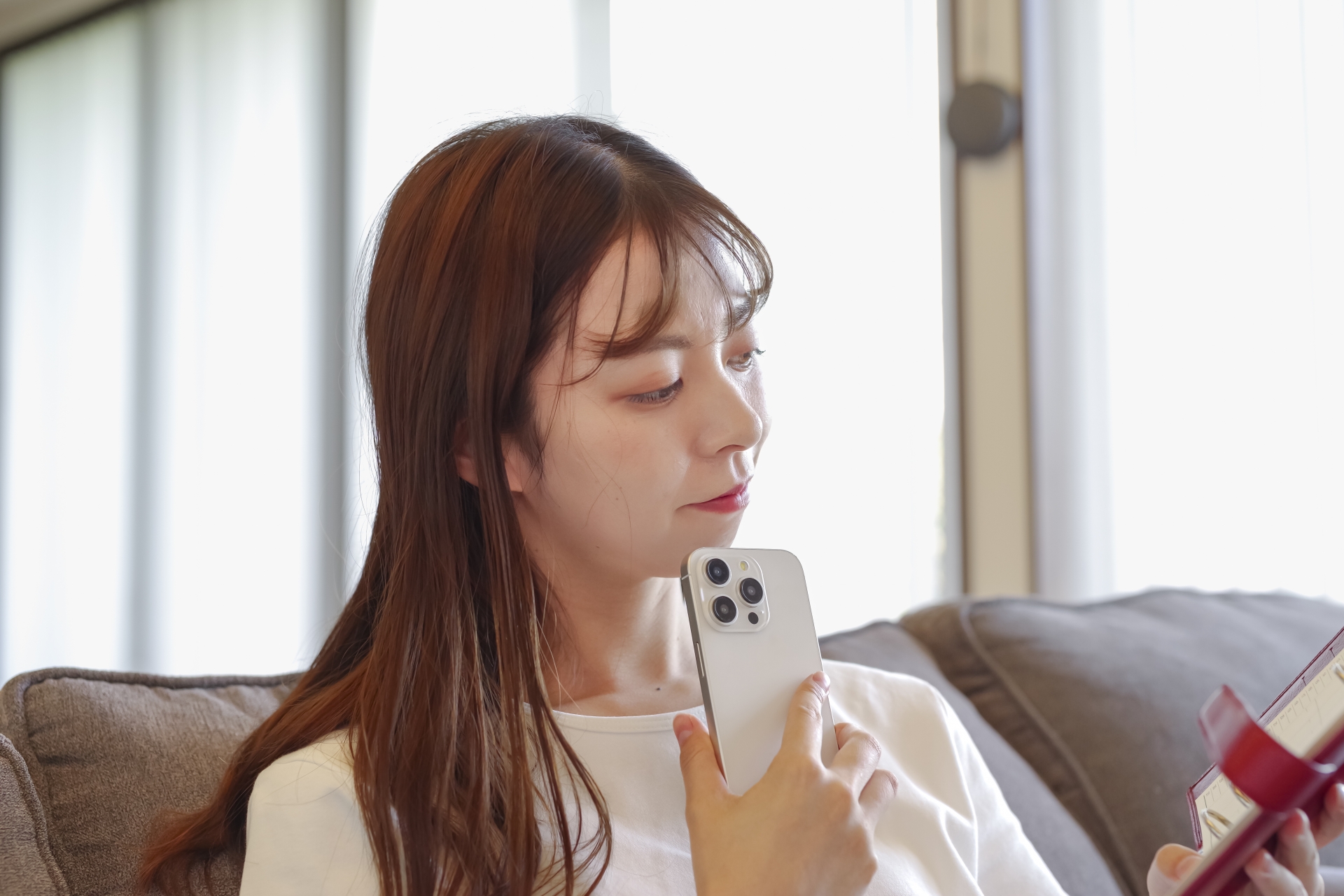 スマホを顎に当てて考える女性