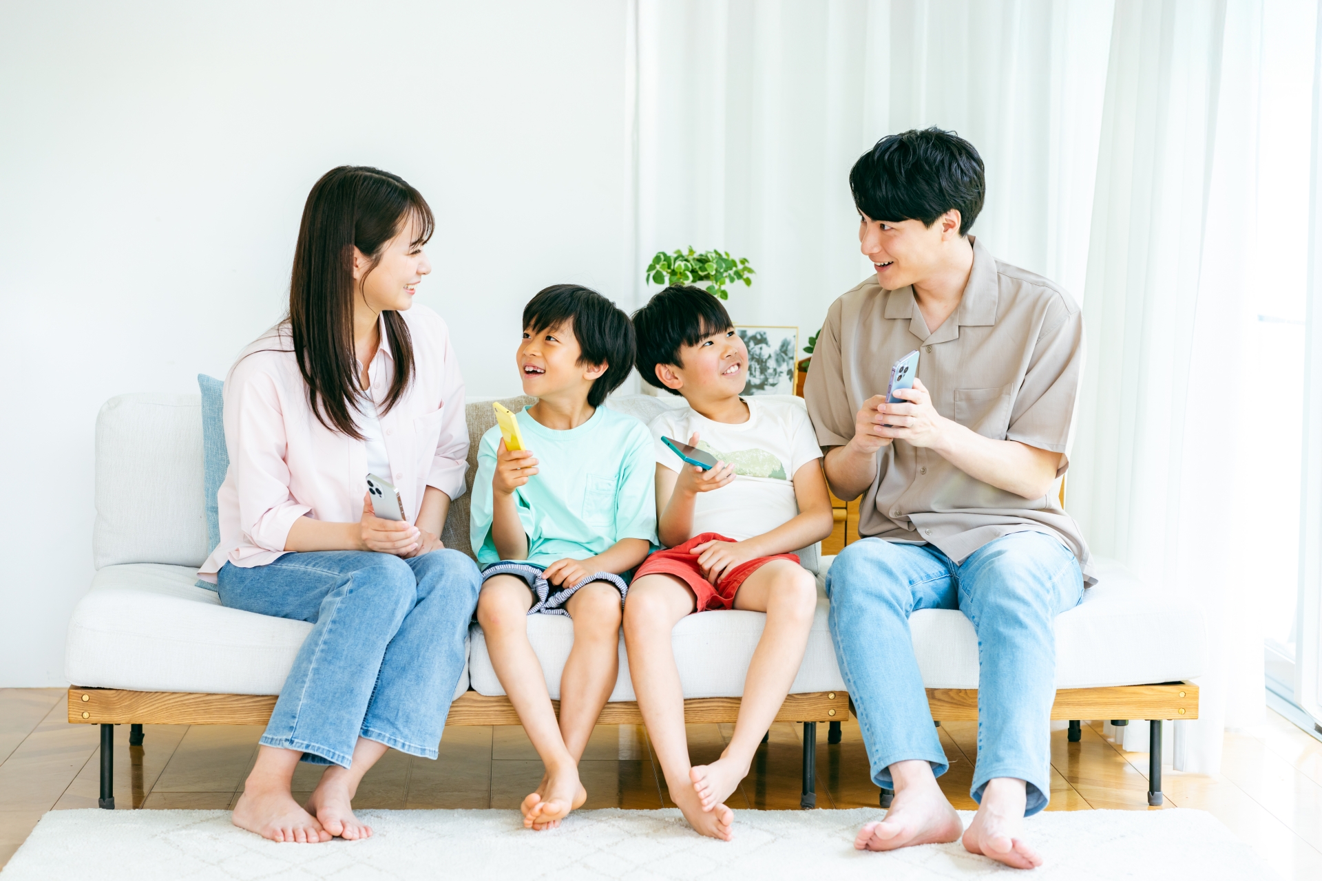 スマホを持ってソファに座る家族