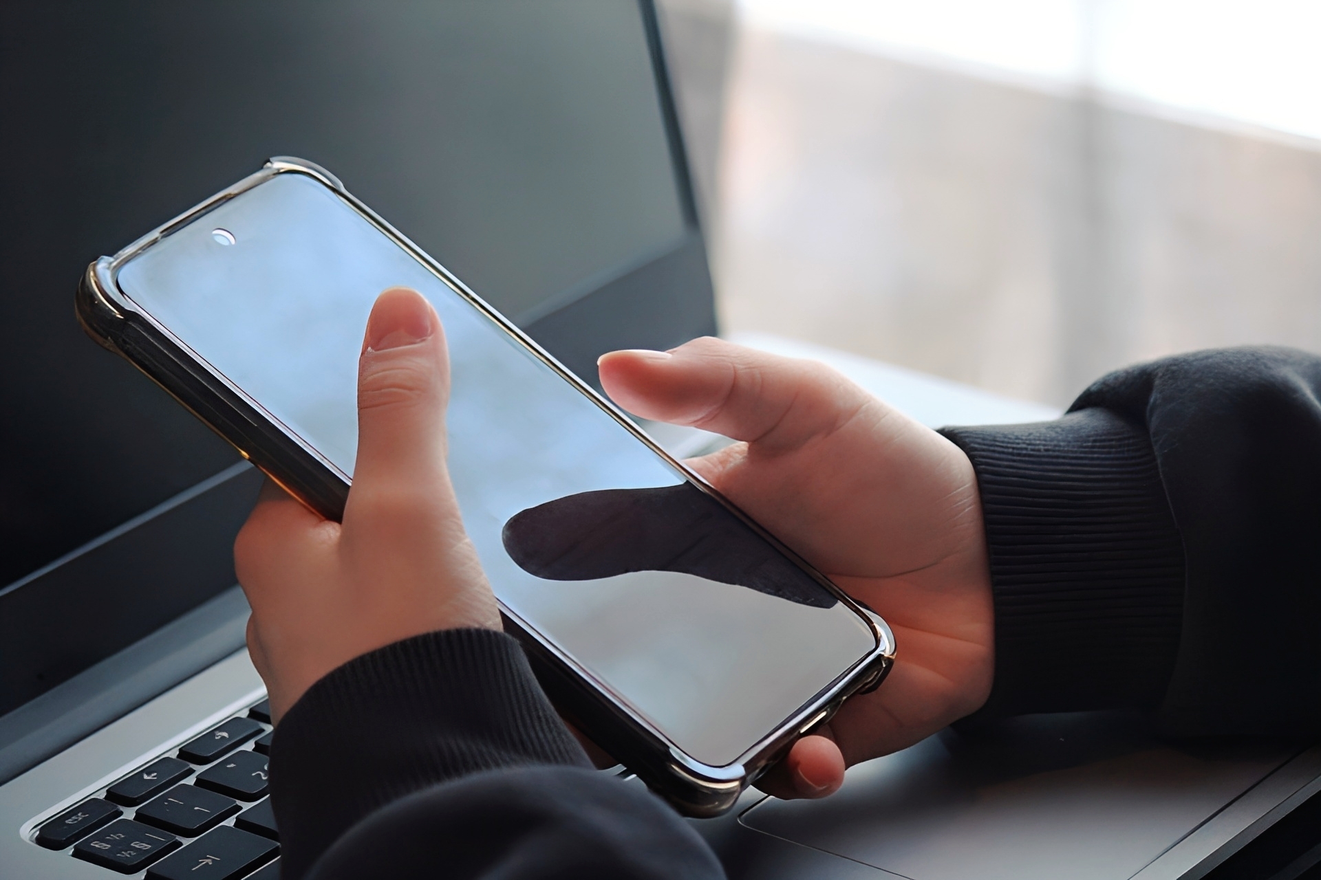 携帯を操作する手元とノートパソコン