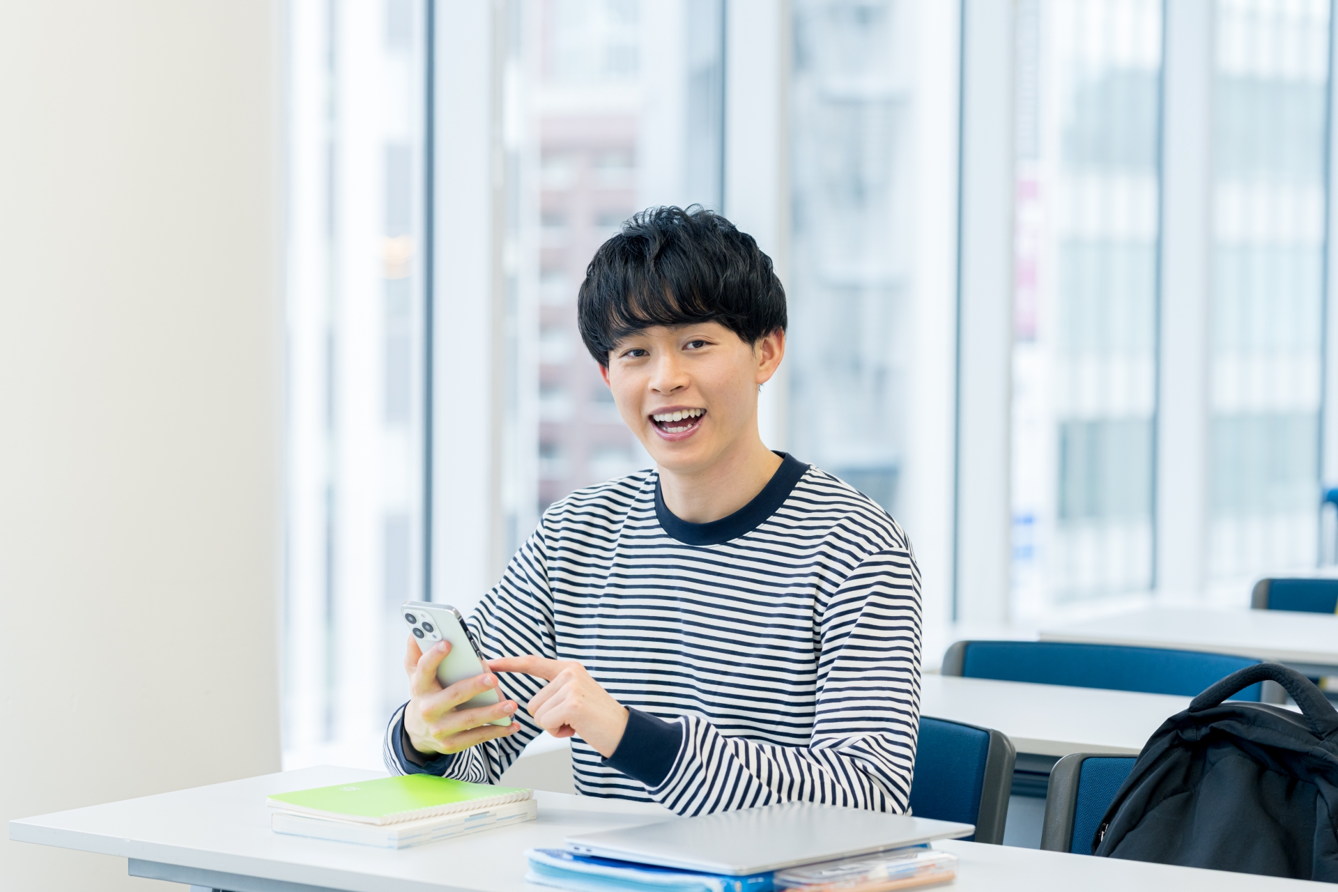 教室でスマホを見る大学生