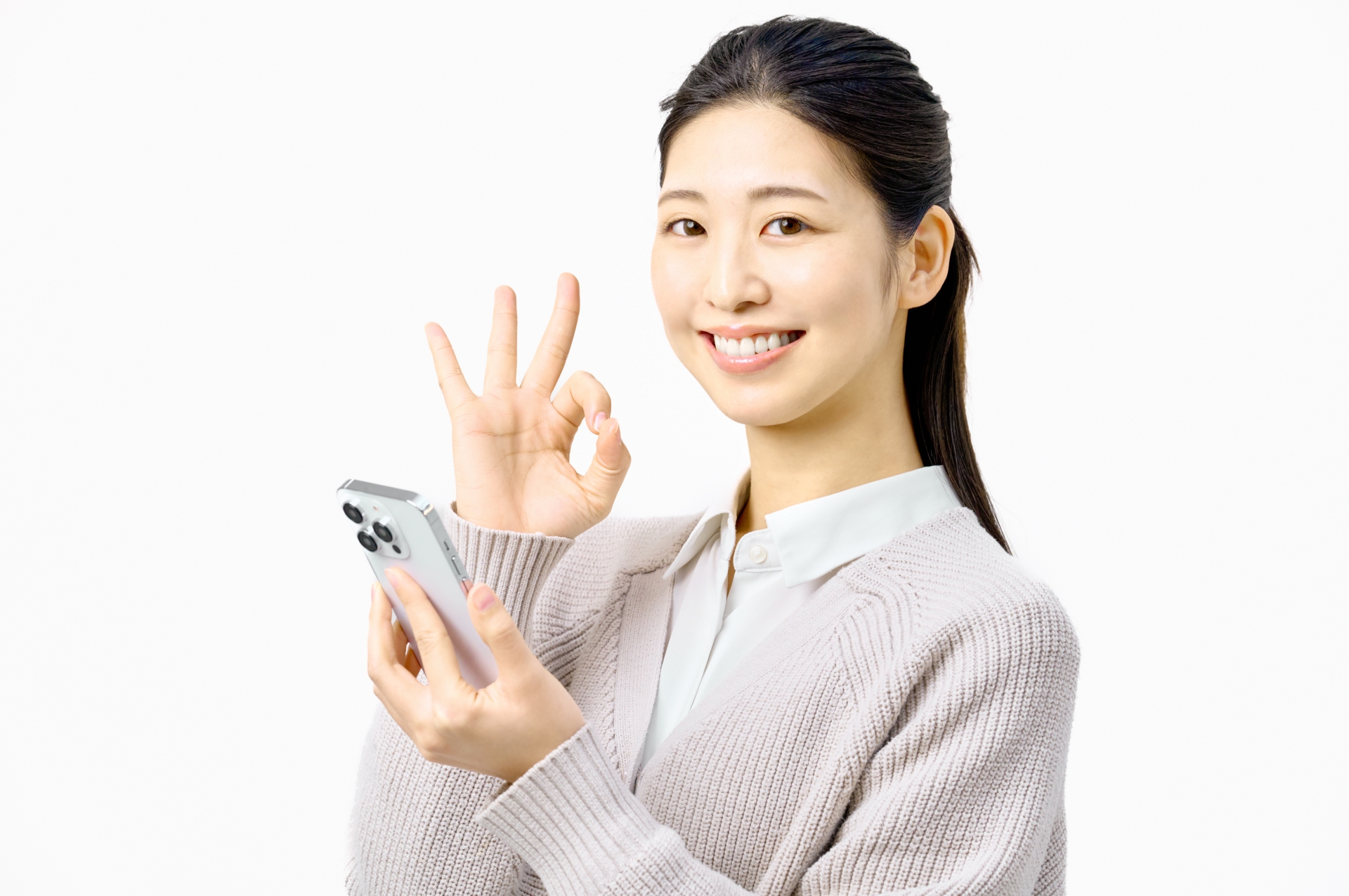 スマートフォンを持ちOKサインする女性