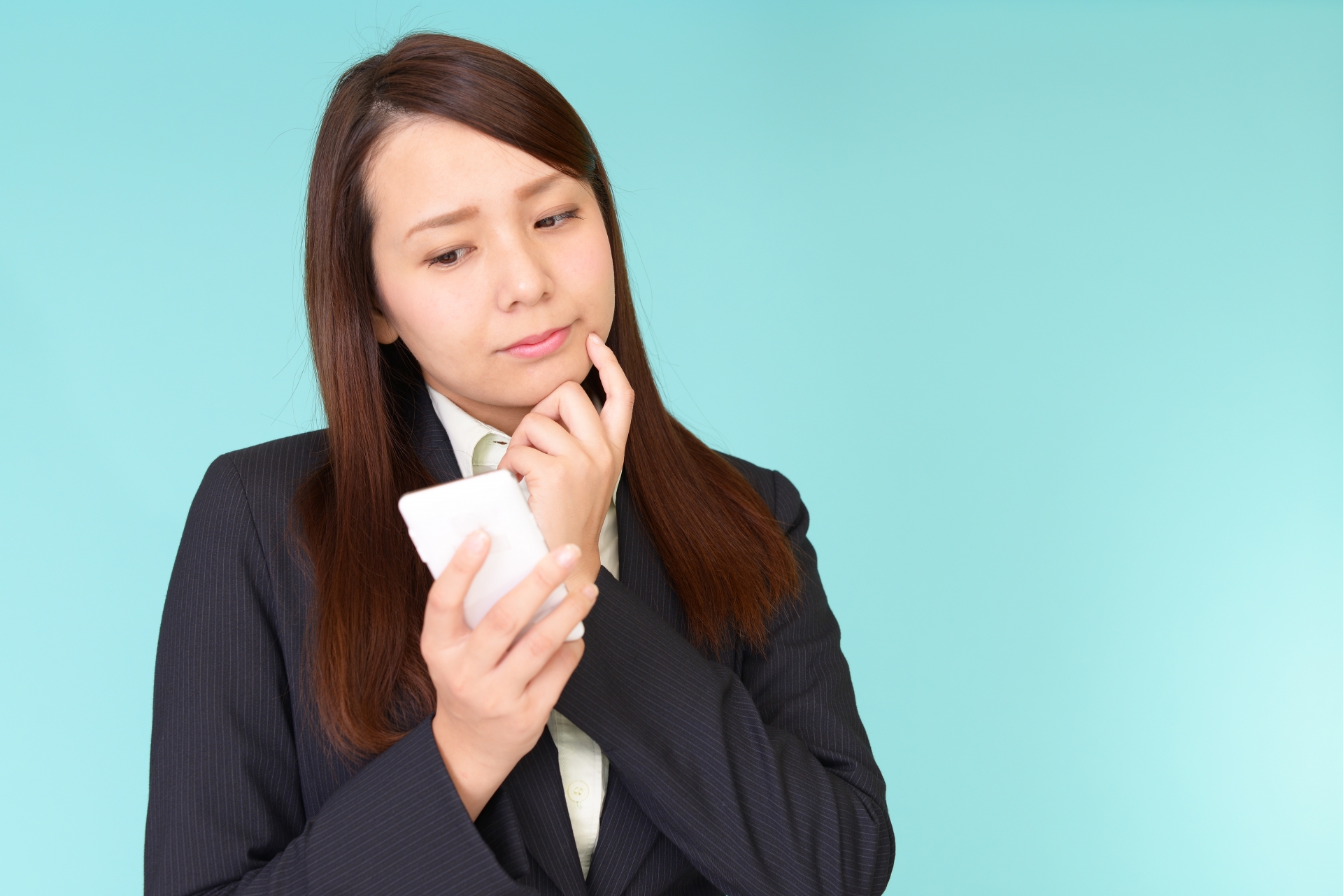 スマートフォンを持って考える女性