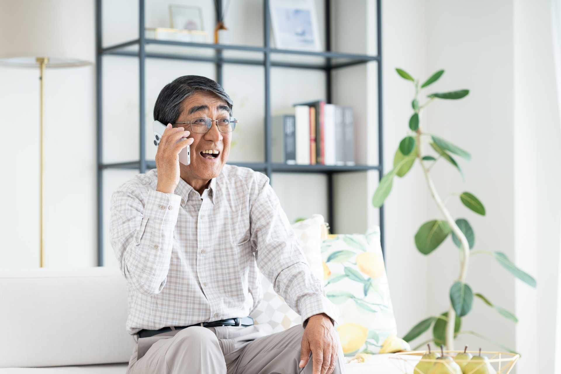 ソファに座って電話するシニアの男性