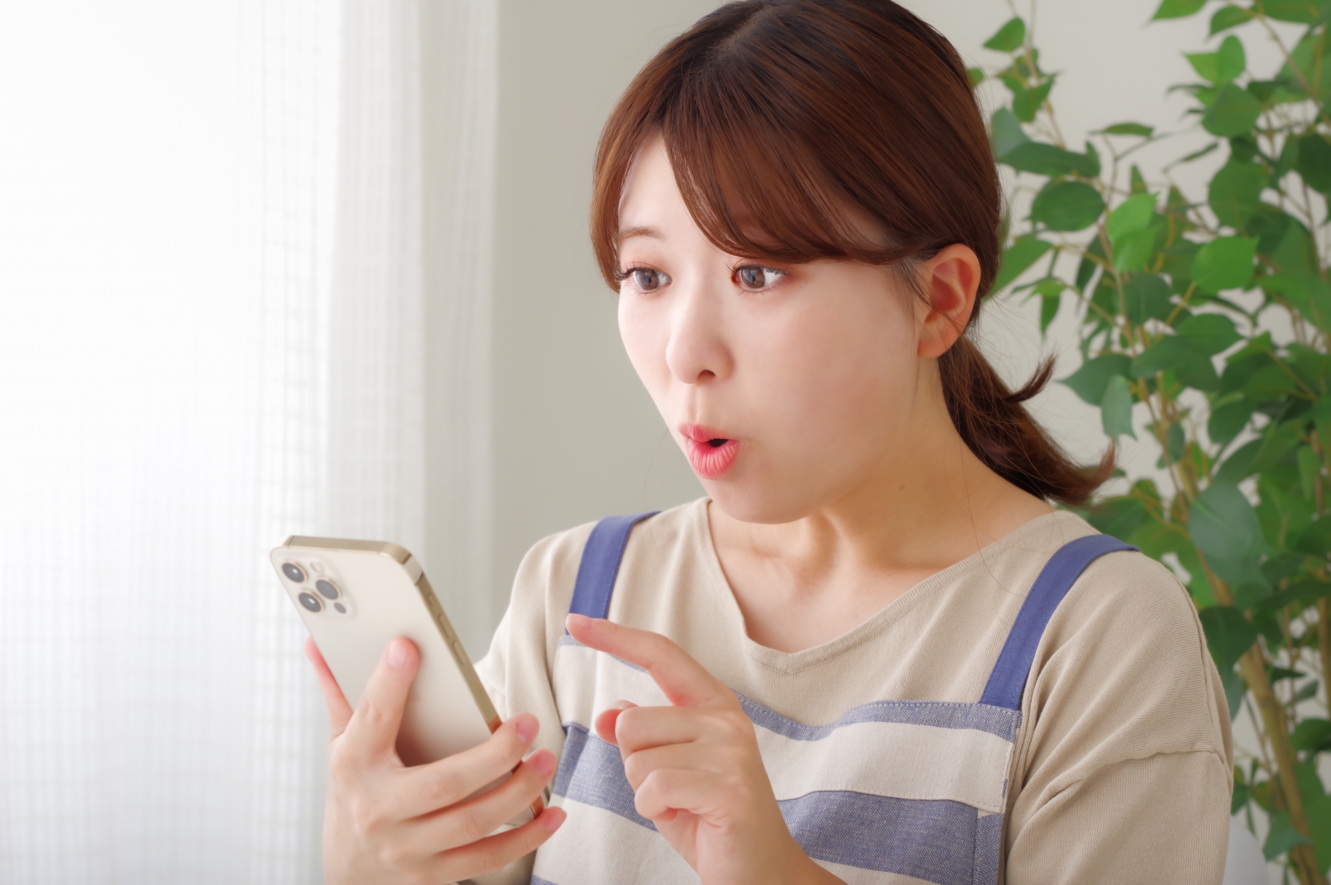 驚いた表情でスマホを持つエプロン姿の女性