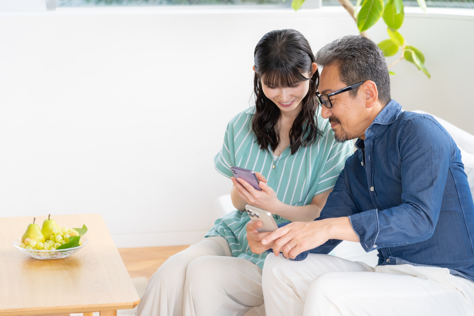 リビングでスマホを見るミドルの夫婦