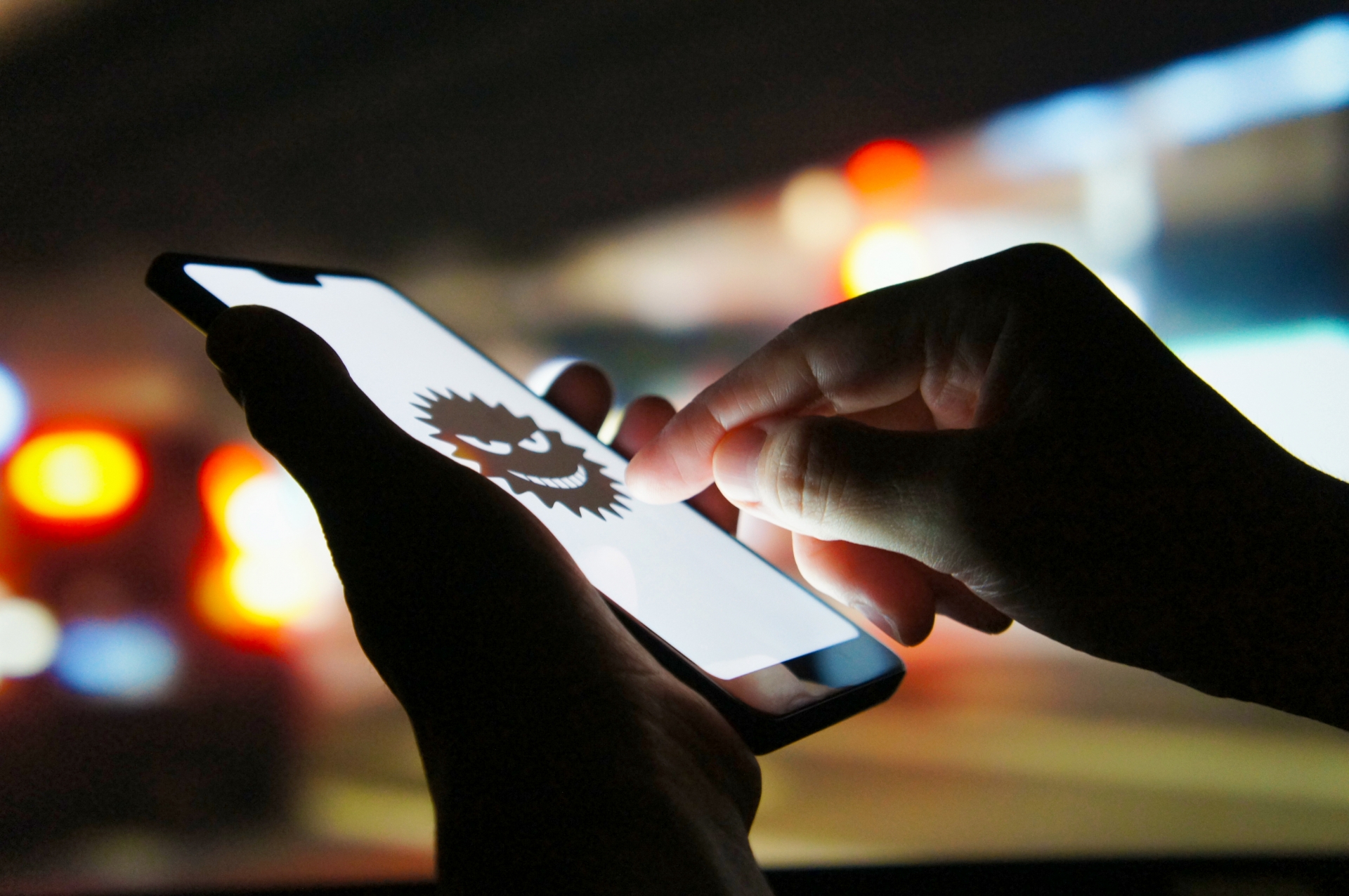 夜の街角にてスマホでサイバー犯罪を企む