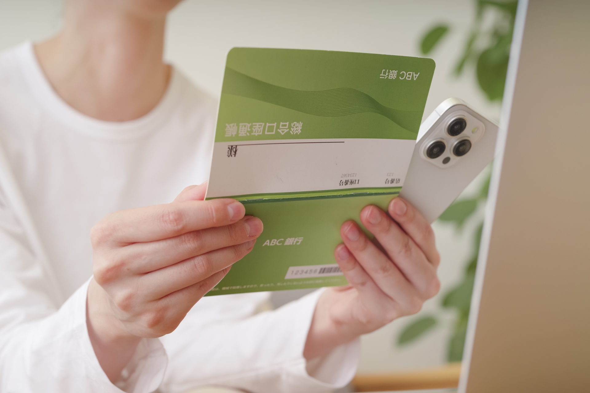 スマホと通帳で金銭のやり取りをする女性