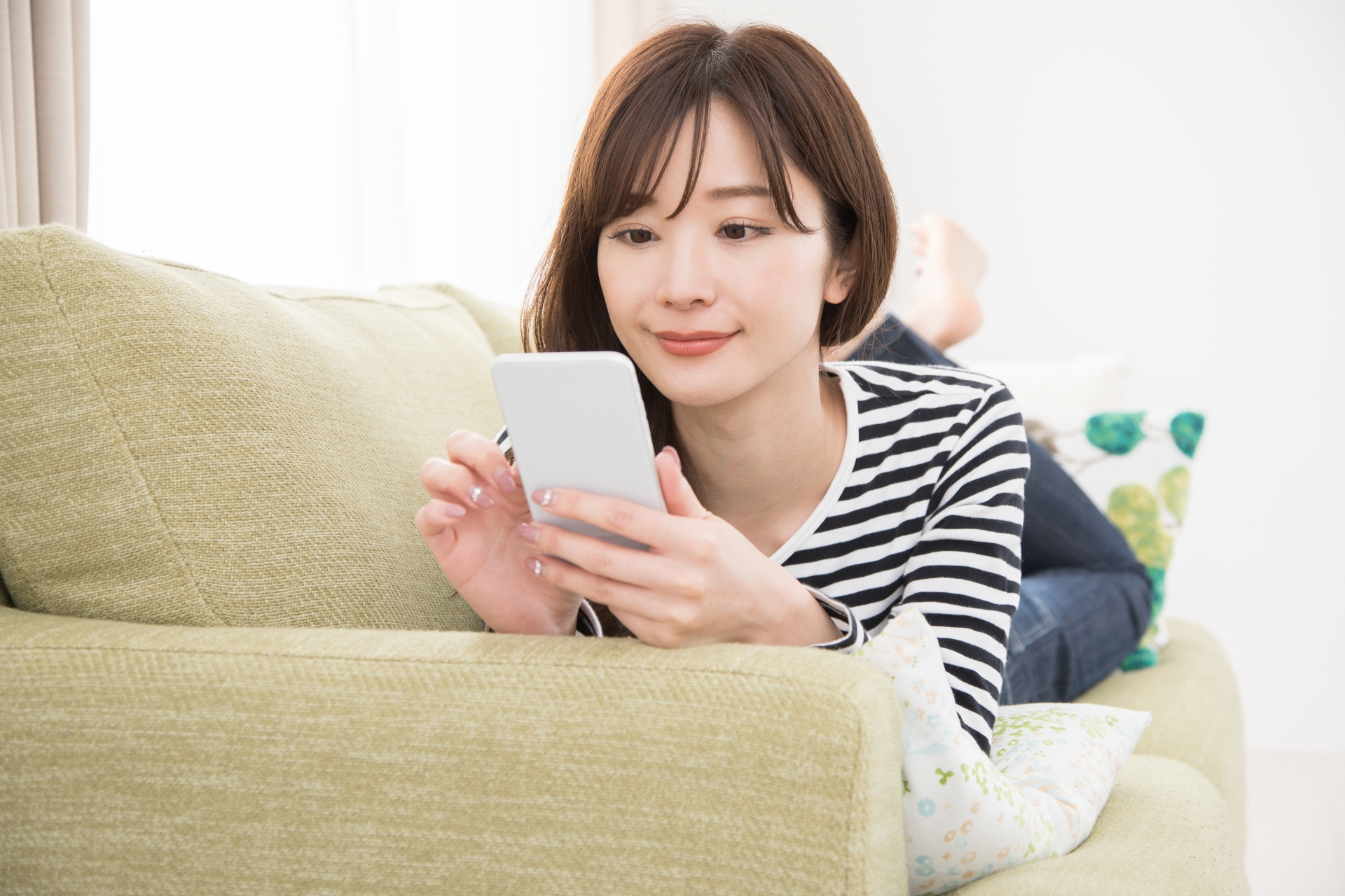 ソファーでスマホを使う女性