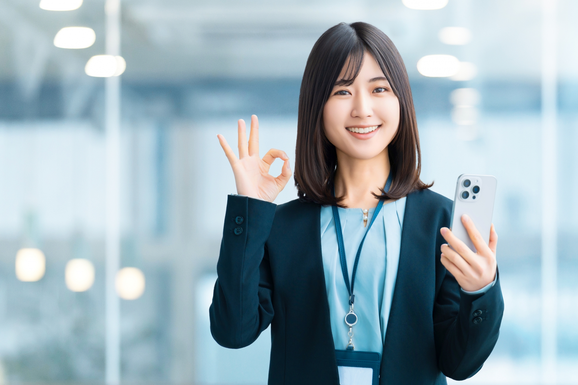 スマホを持ってOKポーズをする笑顔の女性