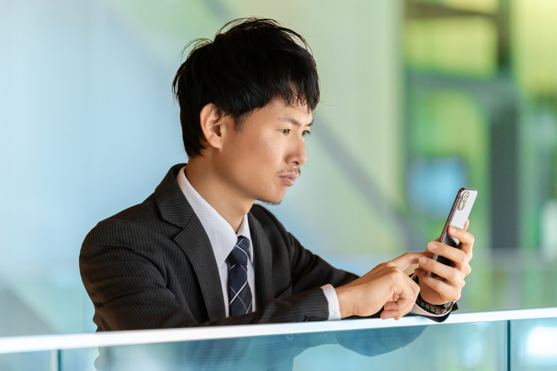 スマホの画面を見て考える男性ビジネスマン