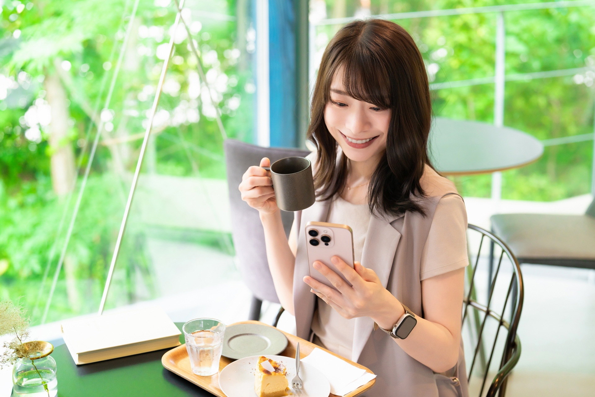 カフェでスマホを使う笑顔の女性