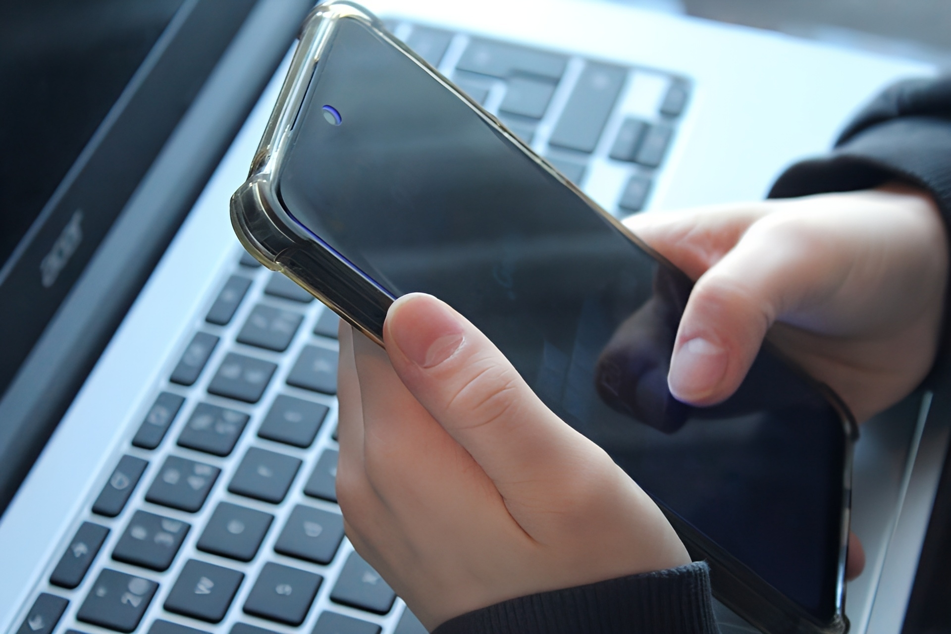 携帯を操作する手元とノートパソコン