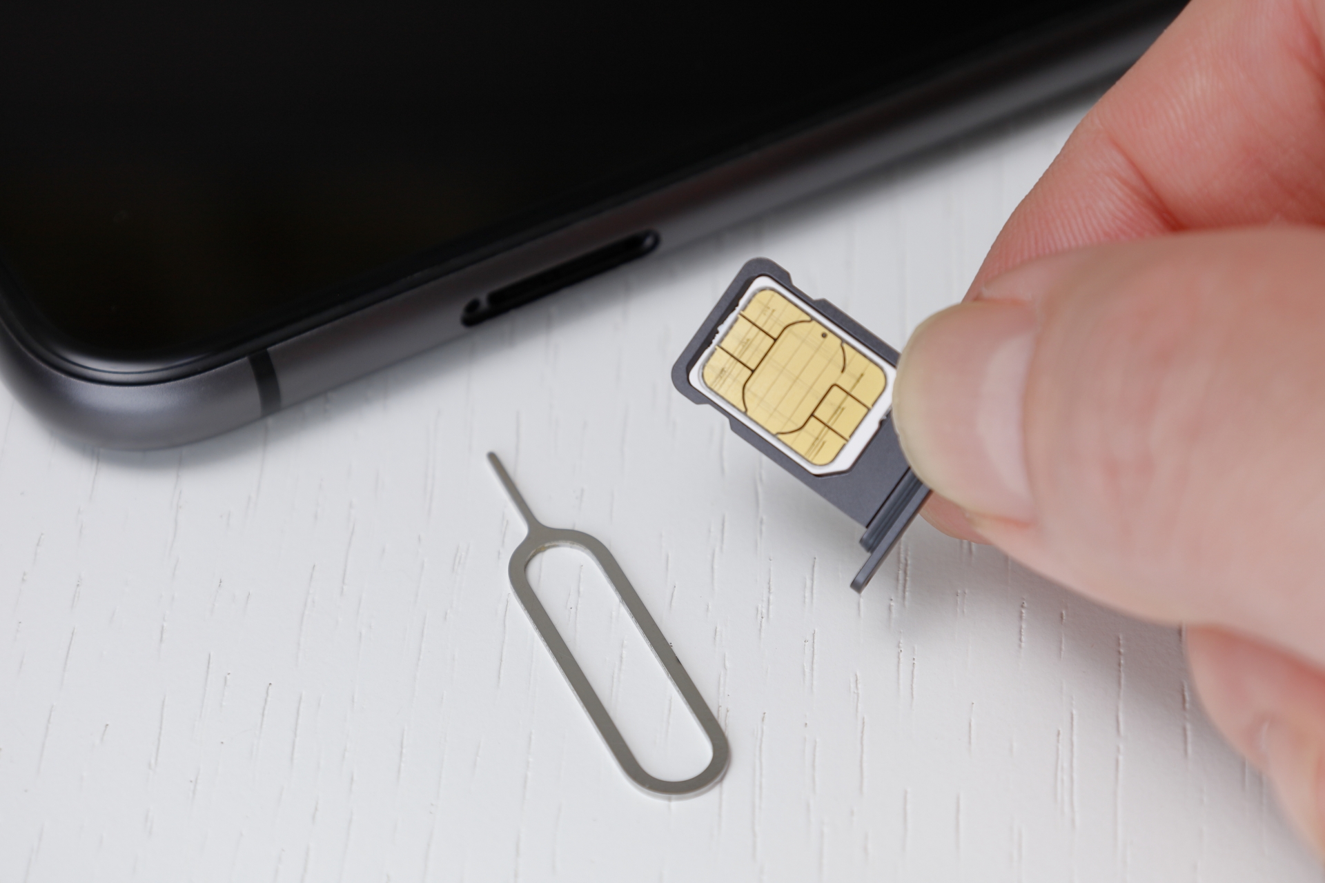 スマートフォンにSIMをセットする右手