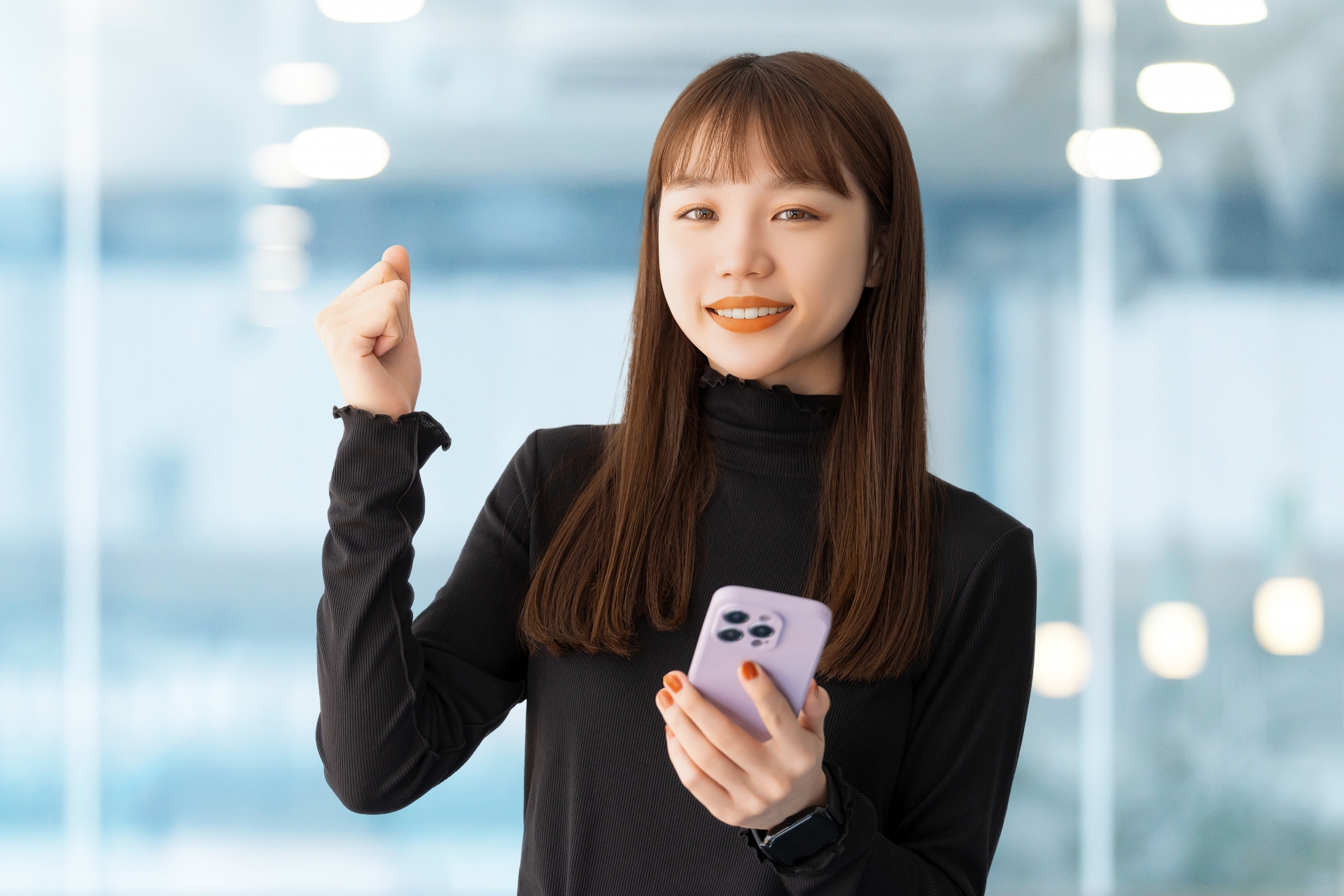 スマホを持ってガッツポーズをする女性