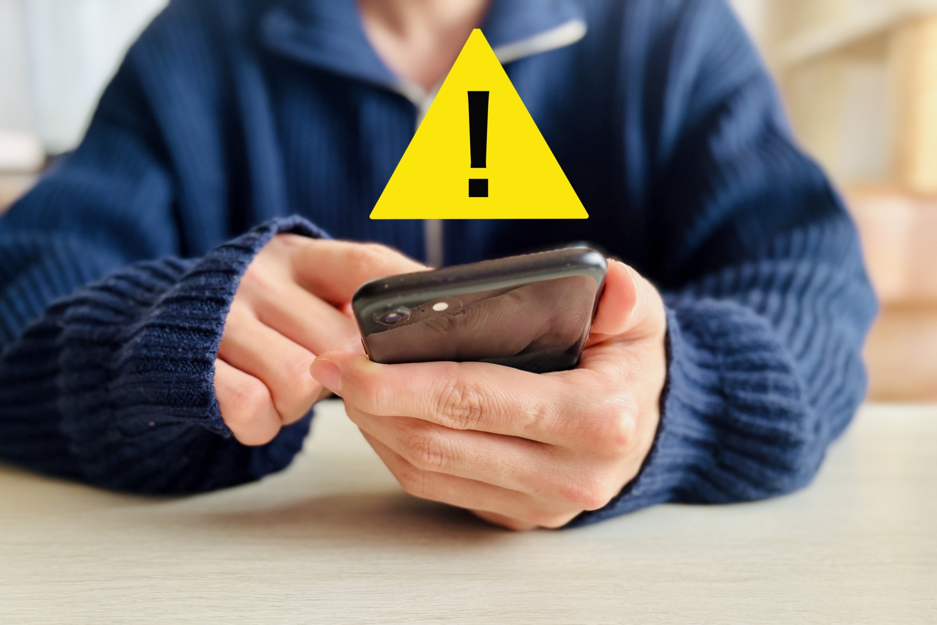 スマホを操作する男性と注意マーク
