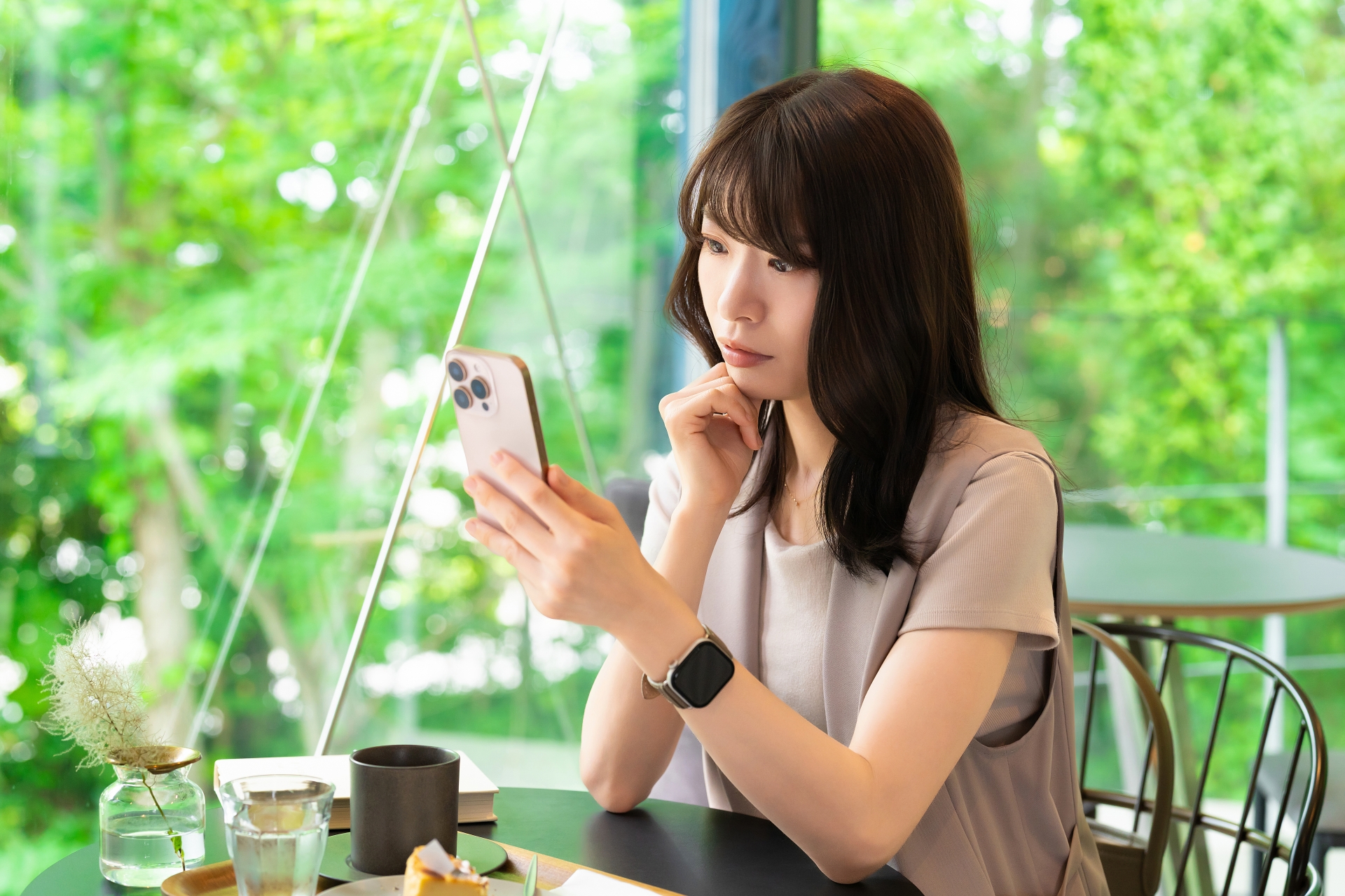 スマホの画面を見て考える女性