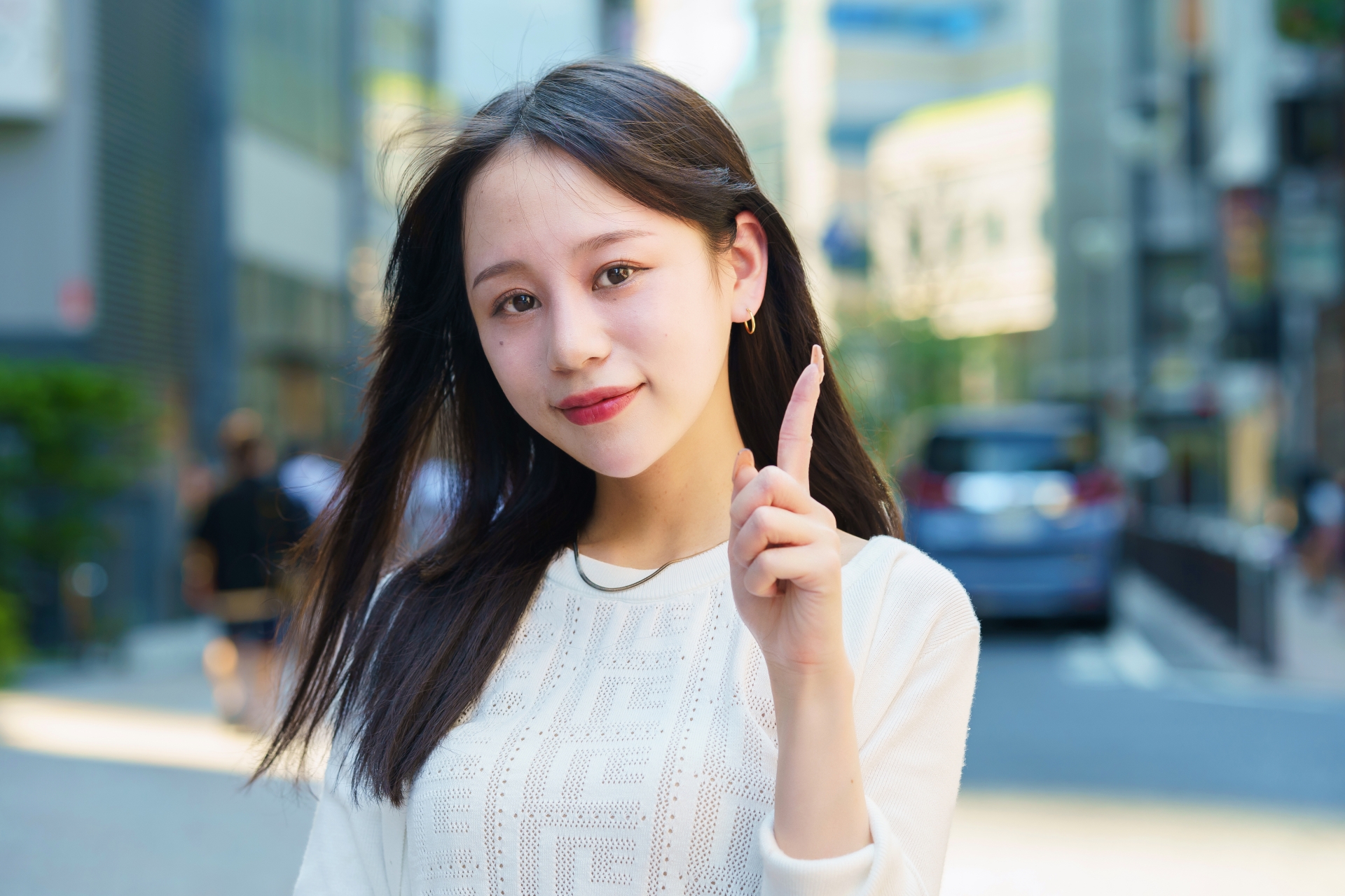 人差し指を上げるポーズをする女性