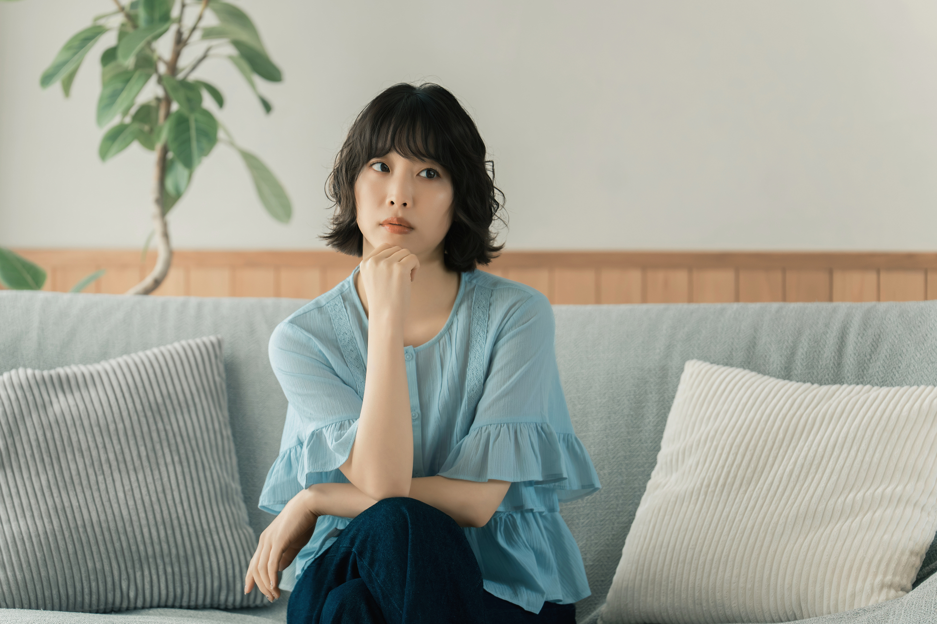 ソファに座って考えごとをする女性