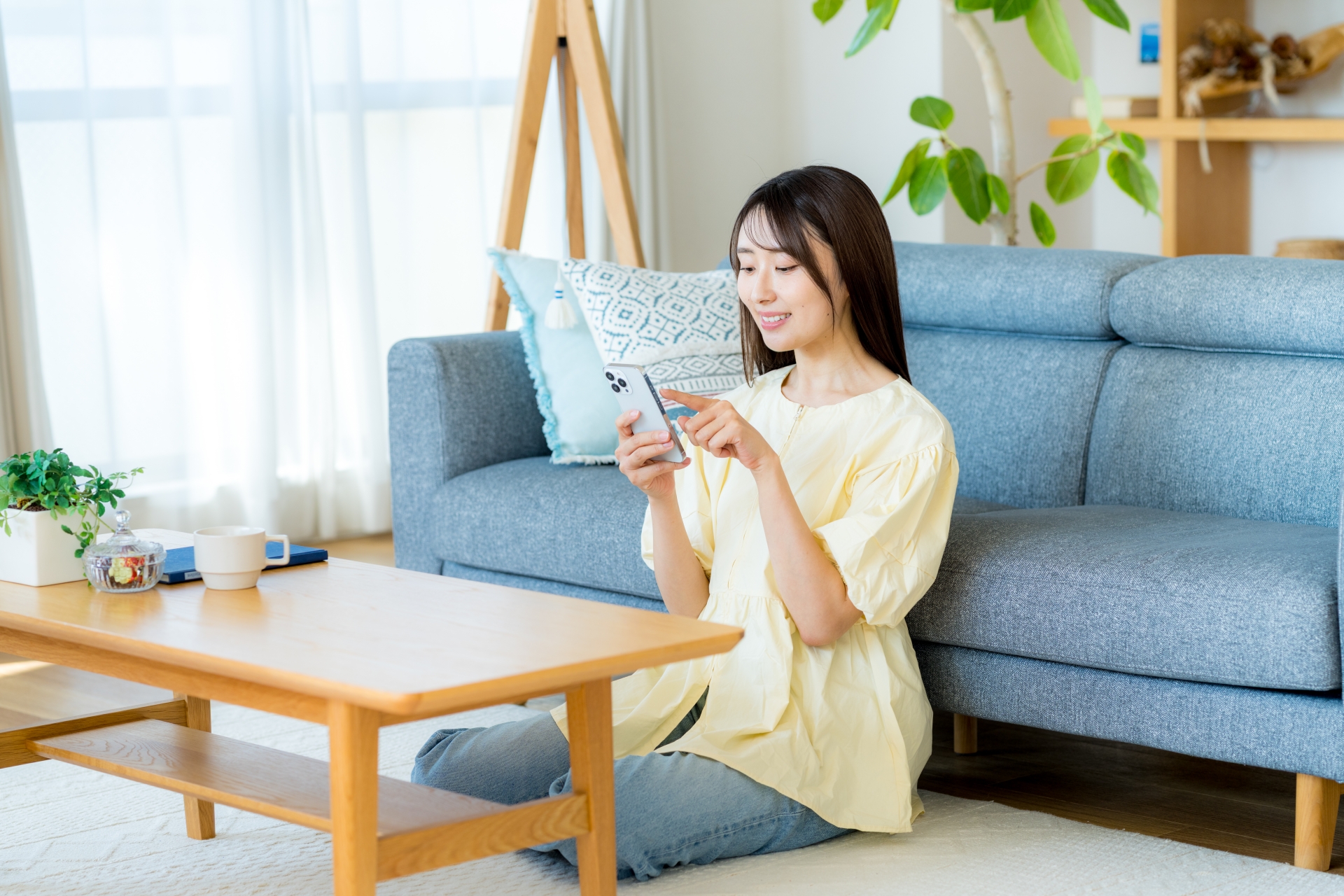 部屋でスマホを操作する女性