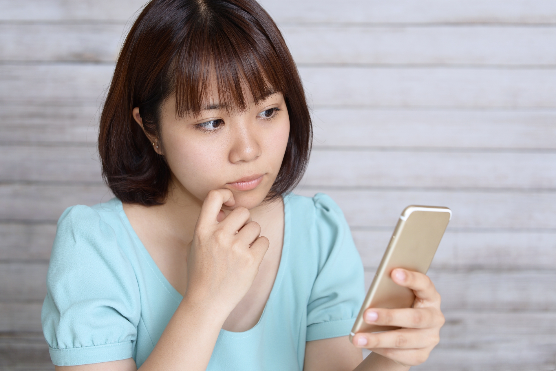 スマートフォンを持って考える女性
