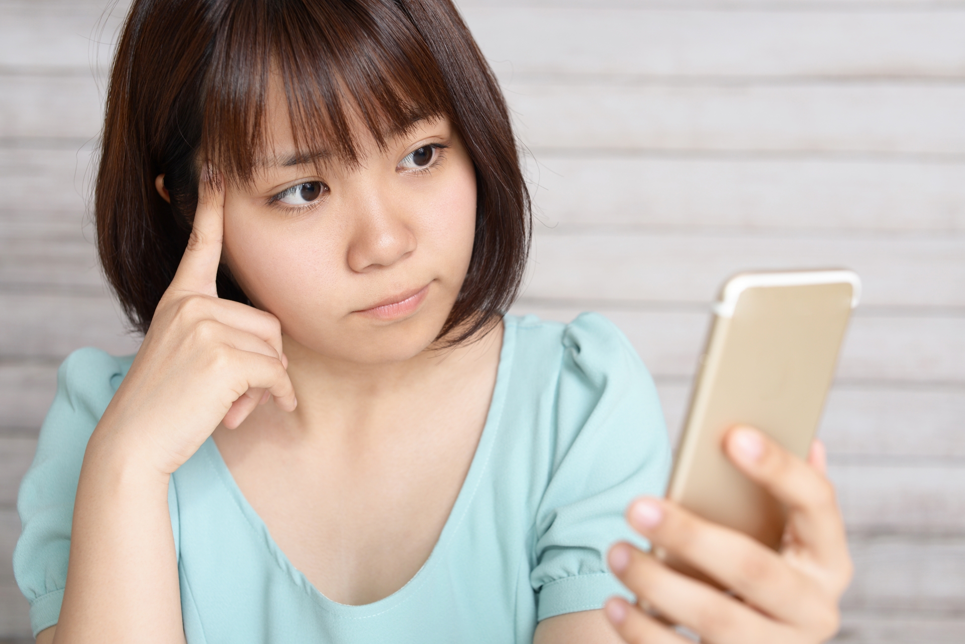 スマホを見て考える女性