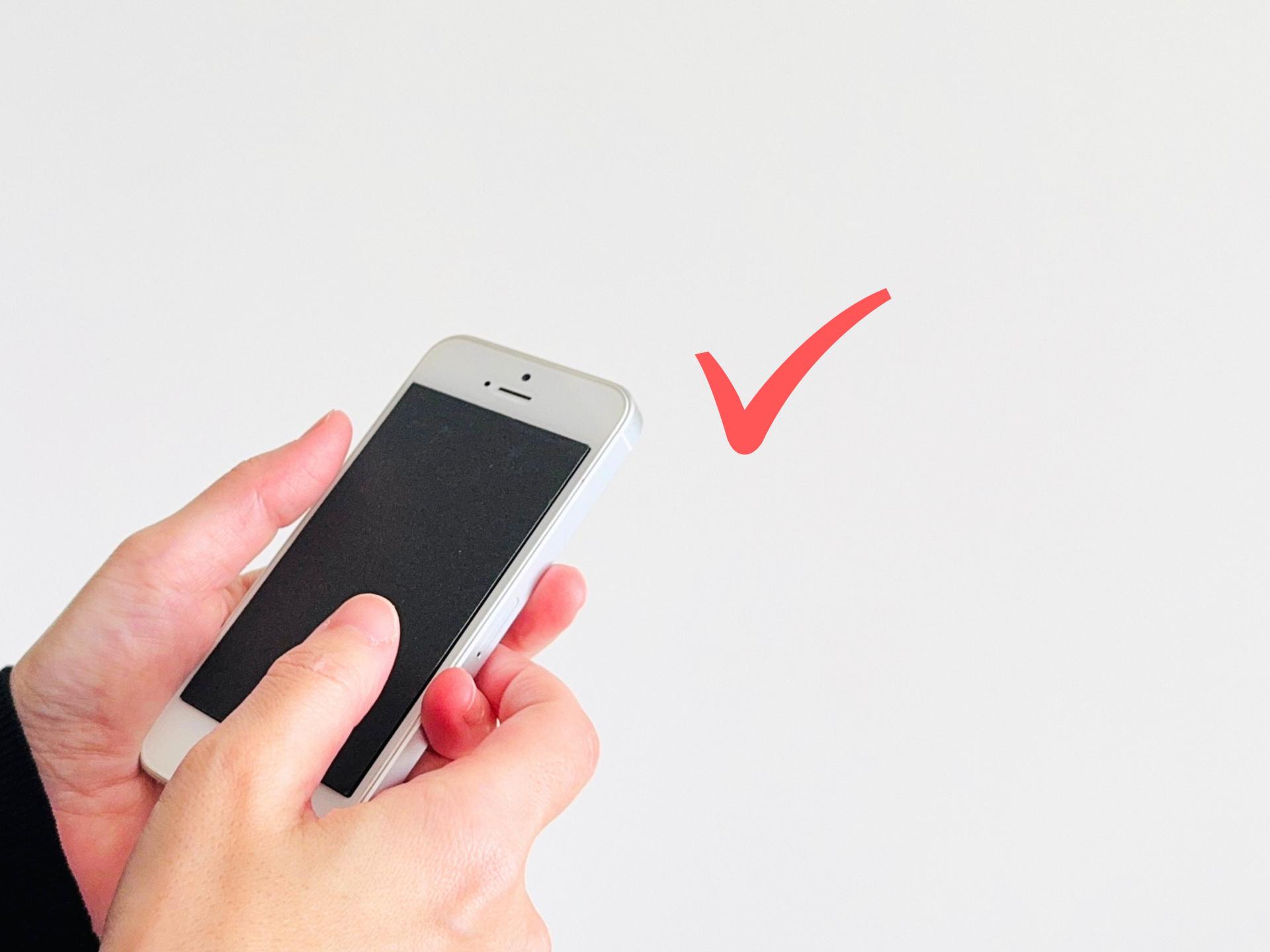 スマートフォンを操作する手元とチェックマーク
