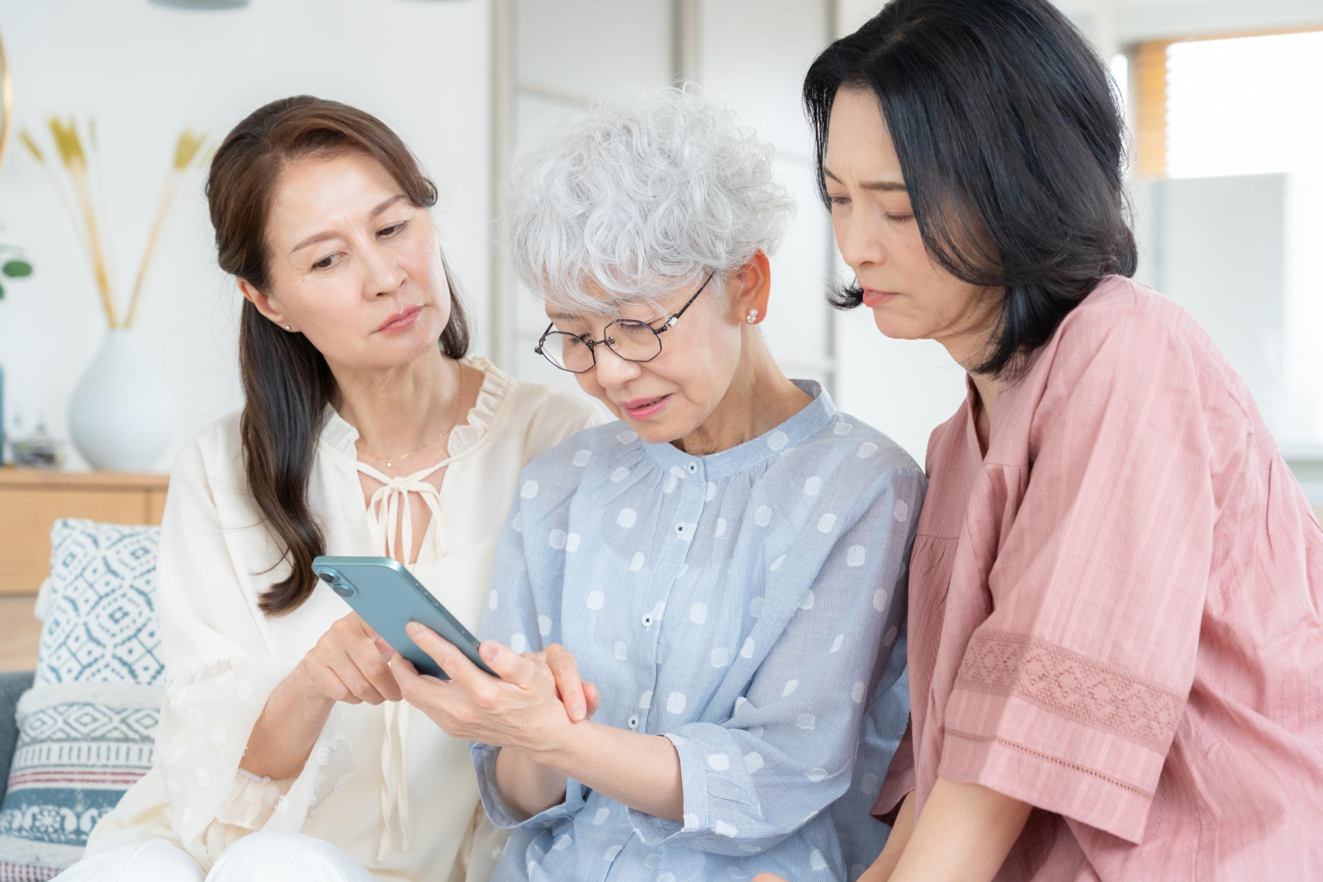 家族と一緒にスマートフォンを確認するシニア女性