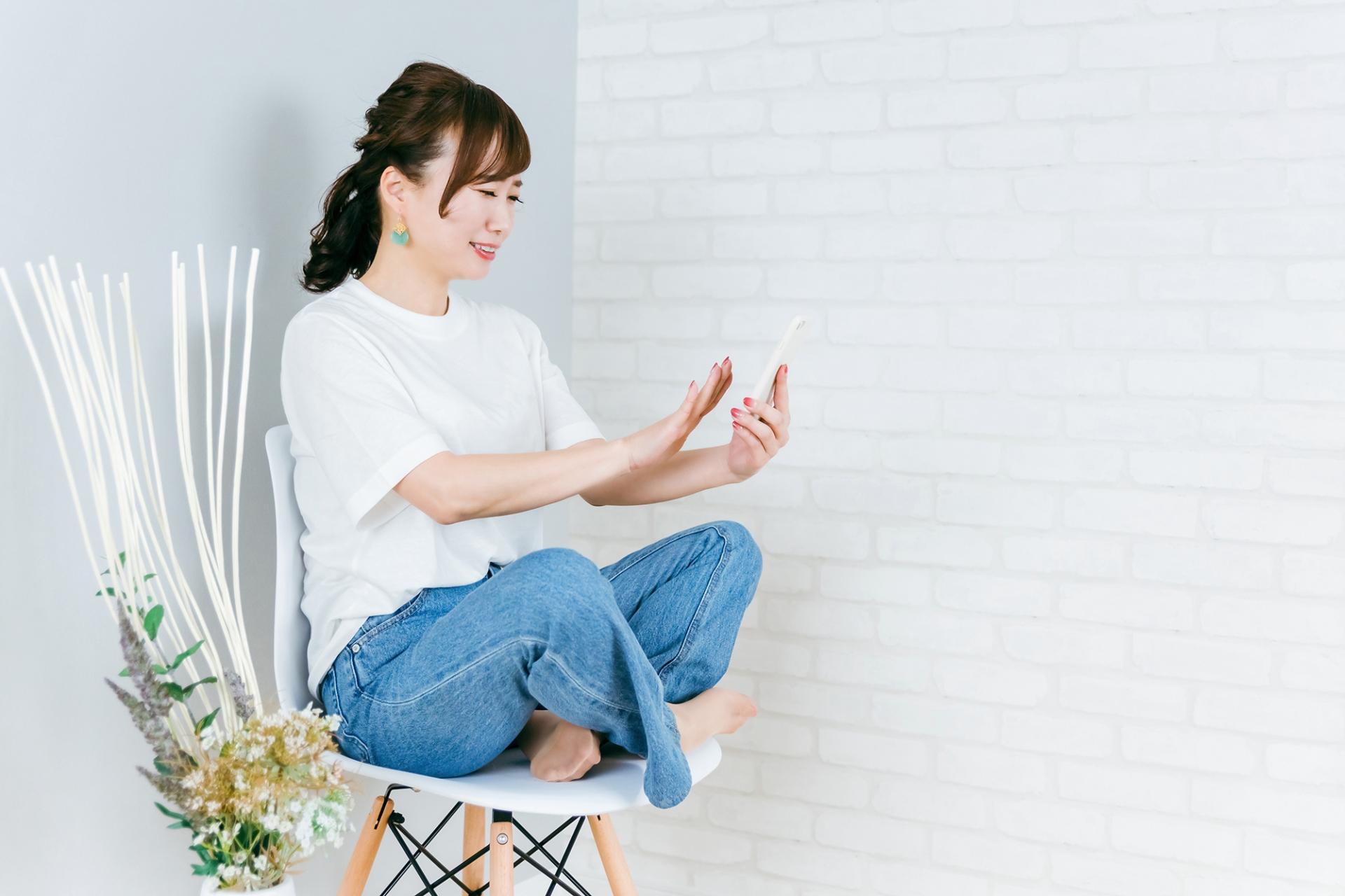 椅子に座ってスマートフォンを確認する女性