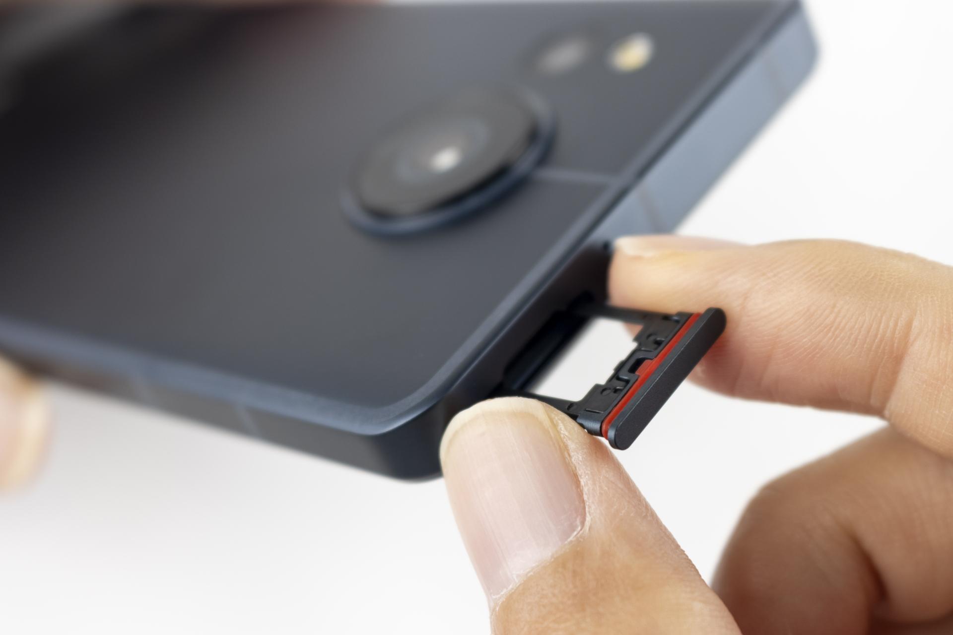 スマートフォンのSIMカードトレイを取り出す手元