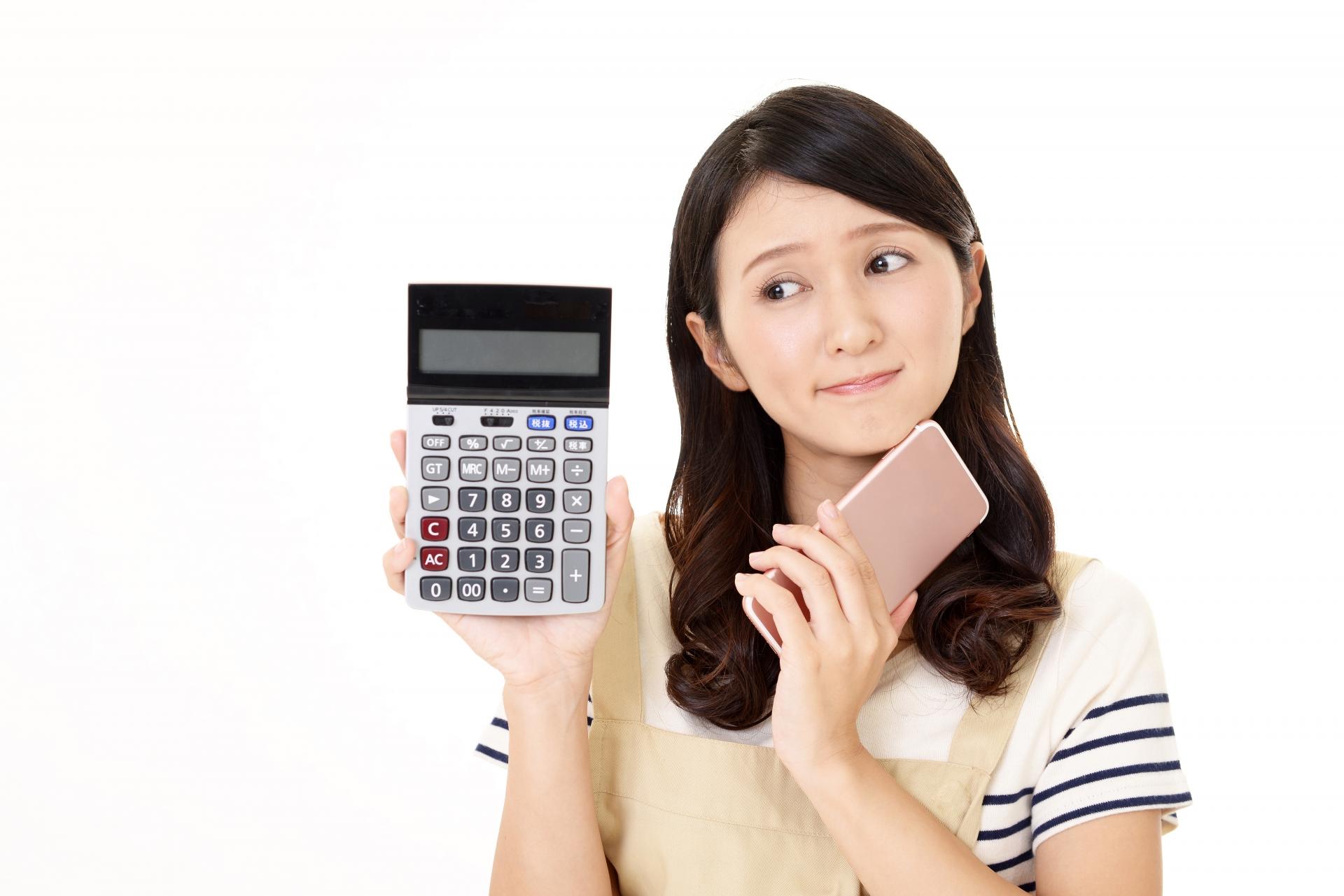 電卓とスマートフォンを持つ女性