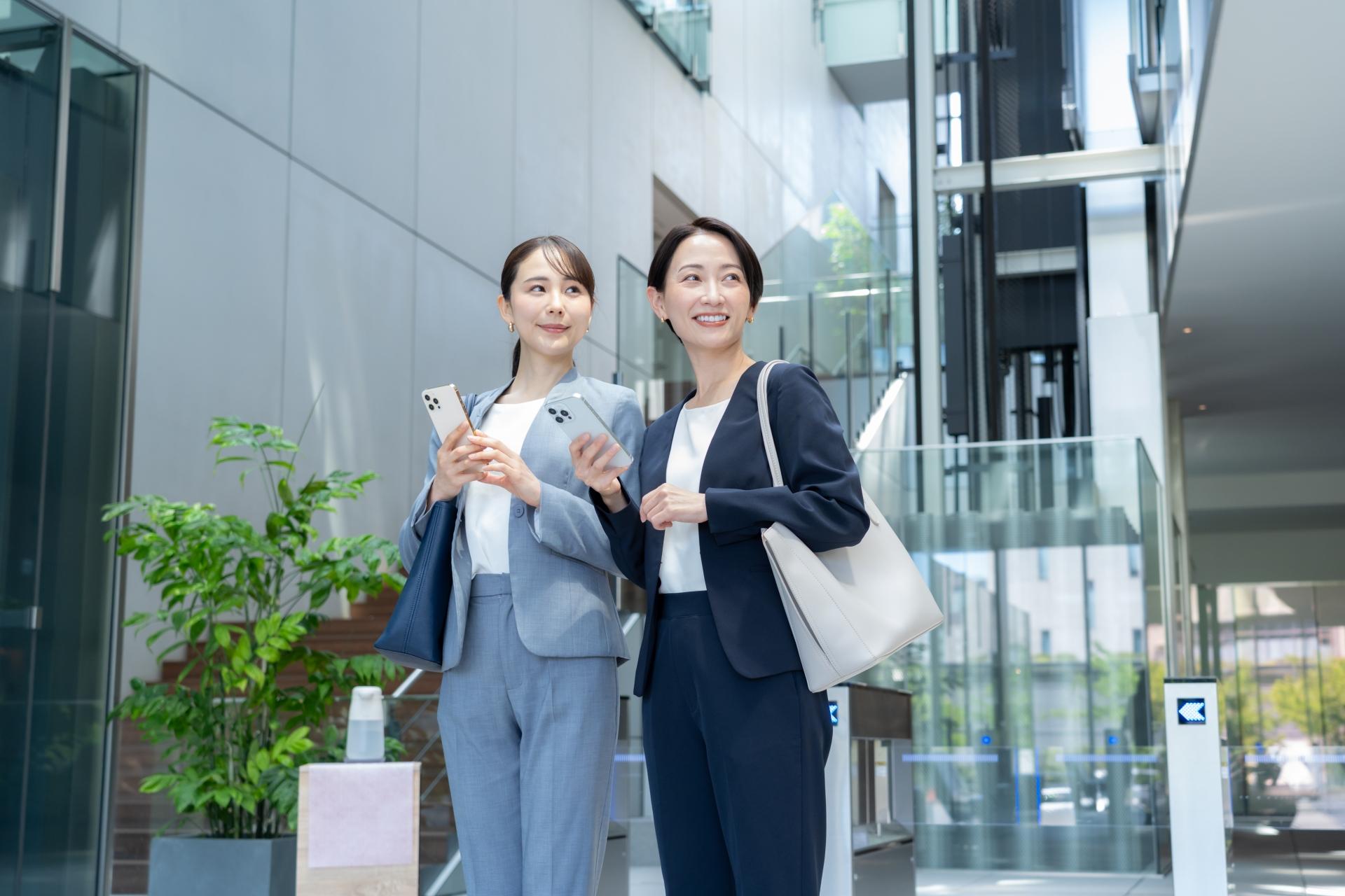 屋外でスマートフォンを持つ2人の女性