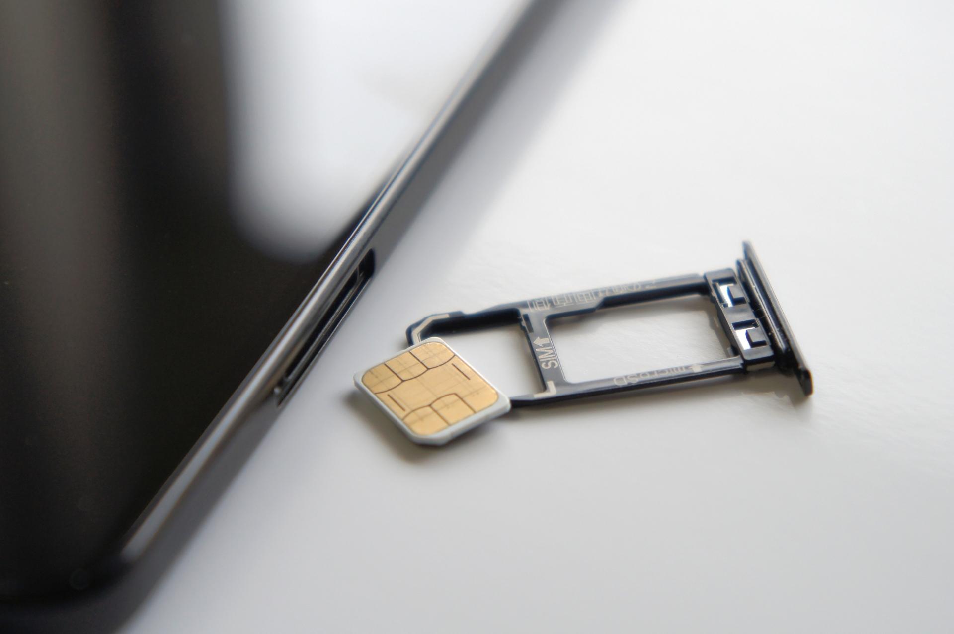 スマートフォンの横に置かれたSIMカードとトレイ