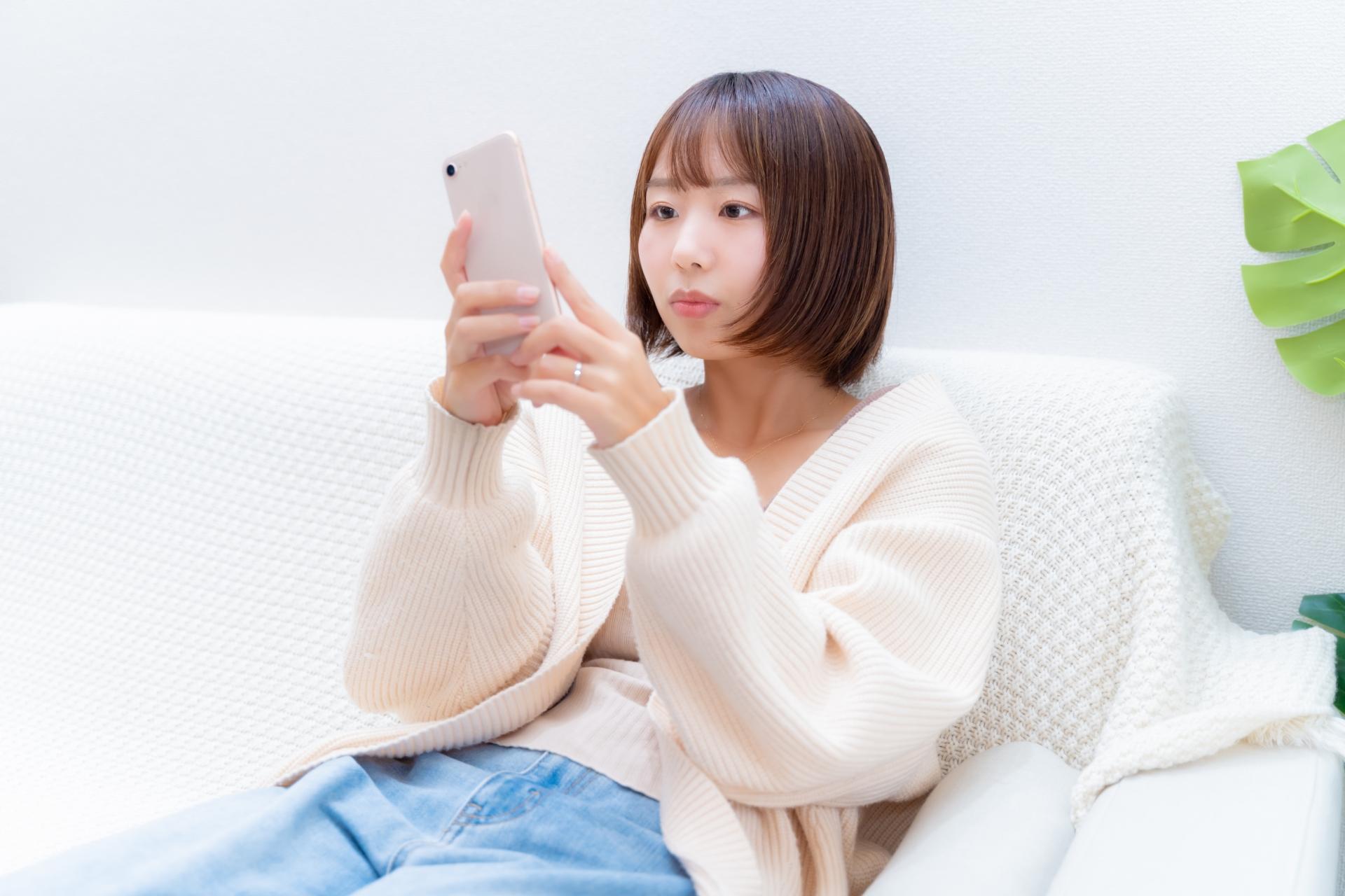 ソファでスマートフォンの画面を確認する女性