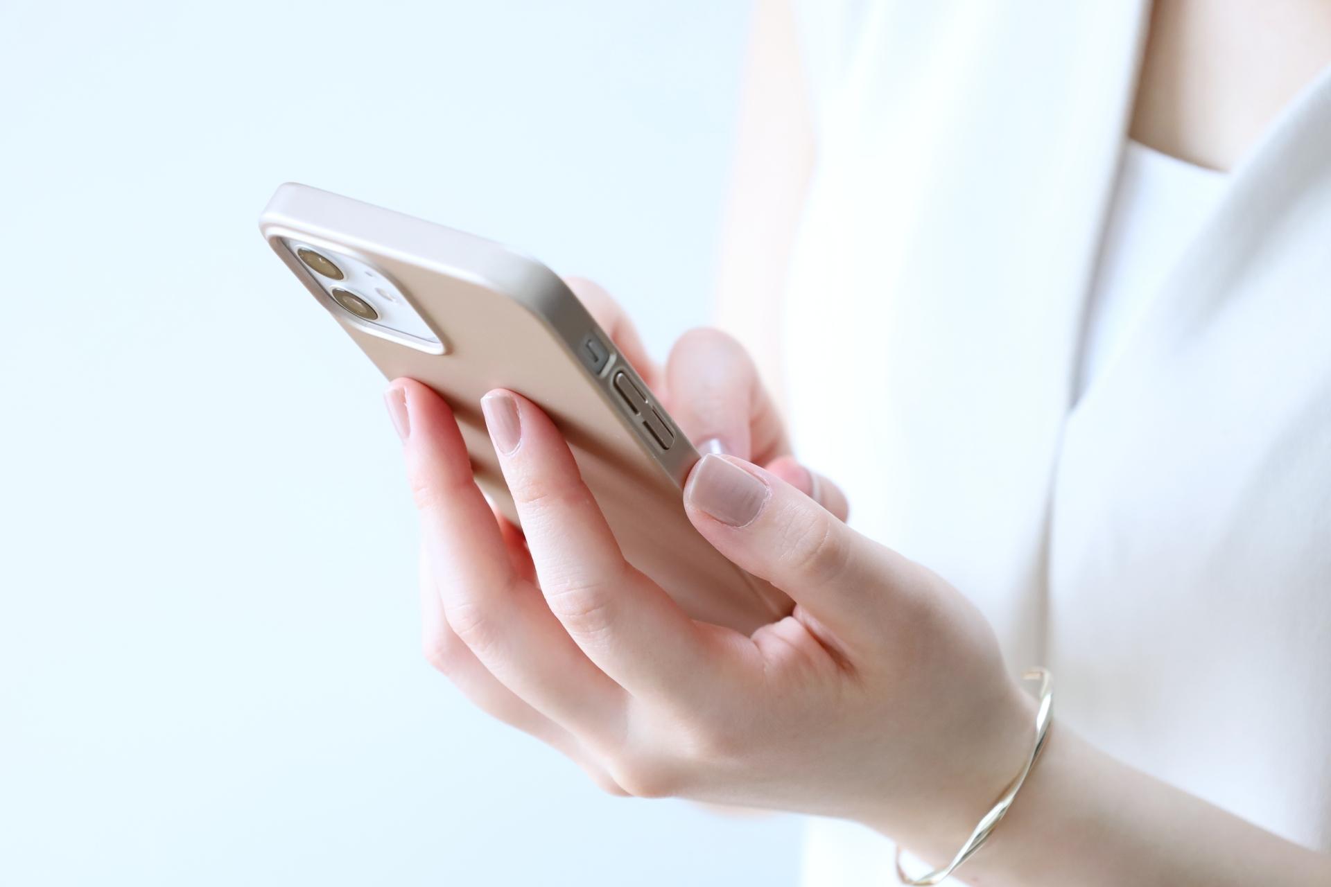 スマートフォンを手に持つ女性の手元