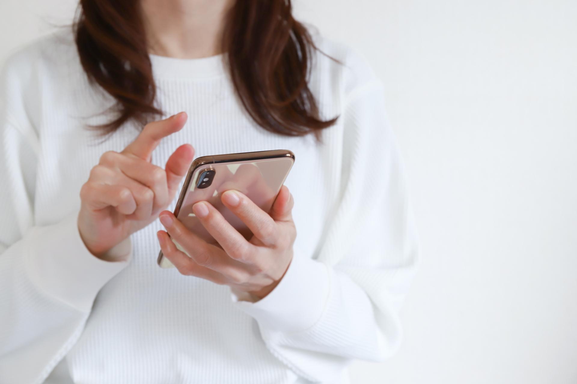 スマートフォンを指で操作する手元