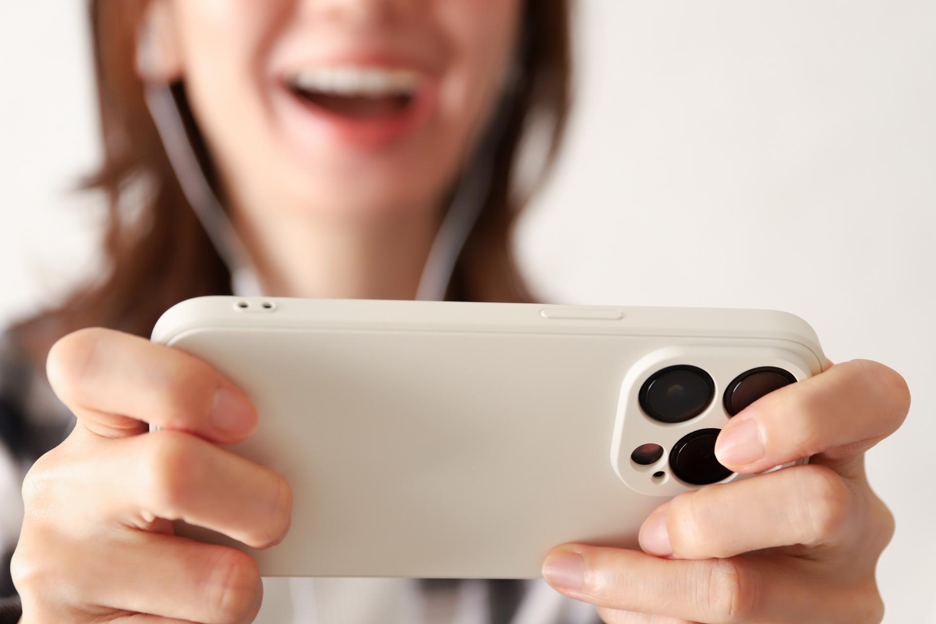 スマートフォンを横向きに持って楽しむ女性