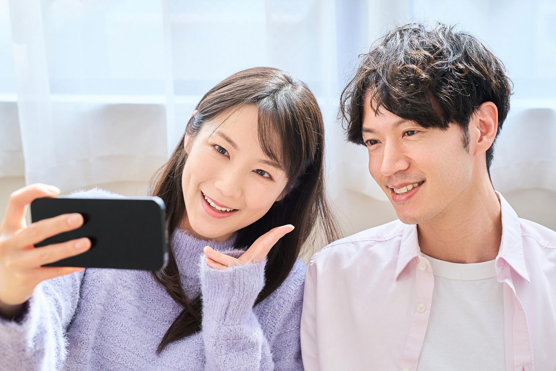 一緒にスマートフォンの画面を見る男女