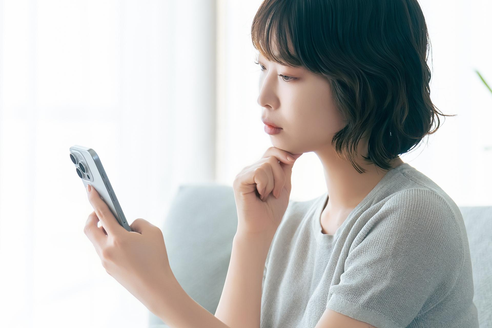 スマートフォンを見て考える女性